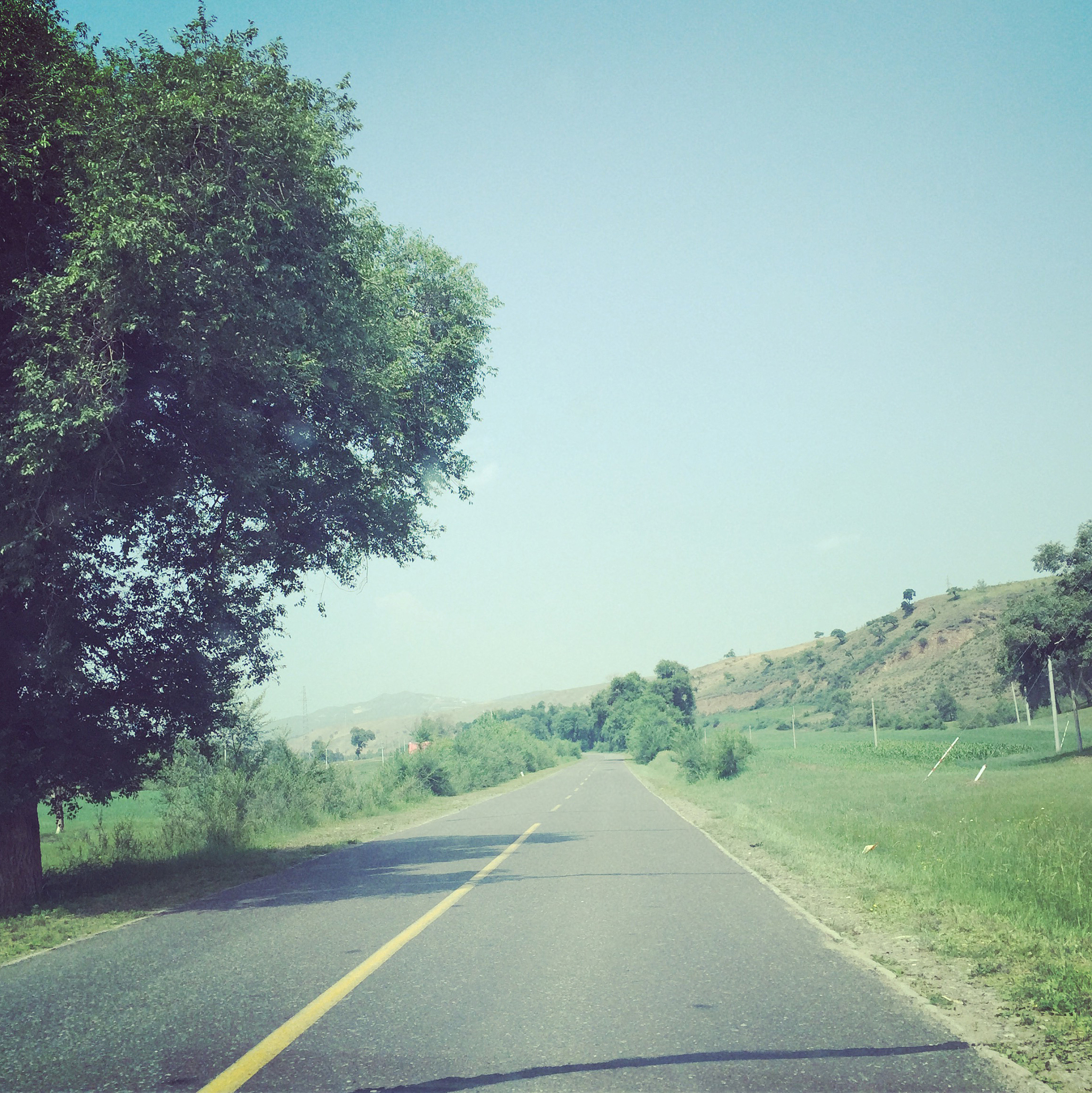 刚下过雨一辆汽车行驶在蜿蜒的山路上四周的草地深绿请用以上文字编写一段伤感文字