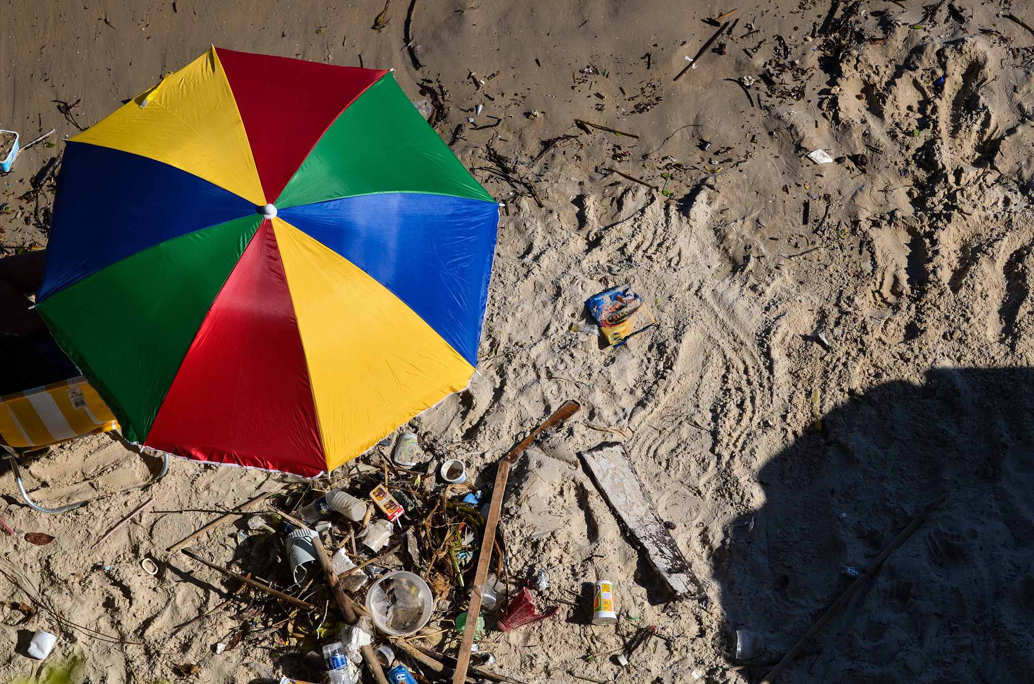 a colorful umbrella seen from above , on a dirty beach .