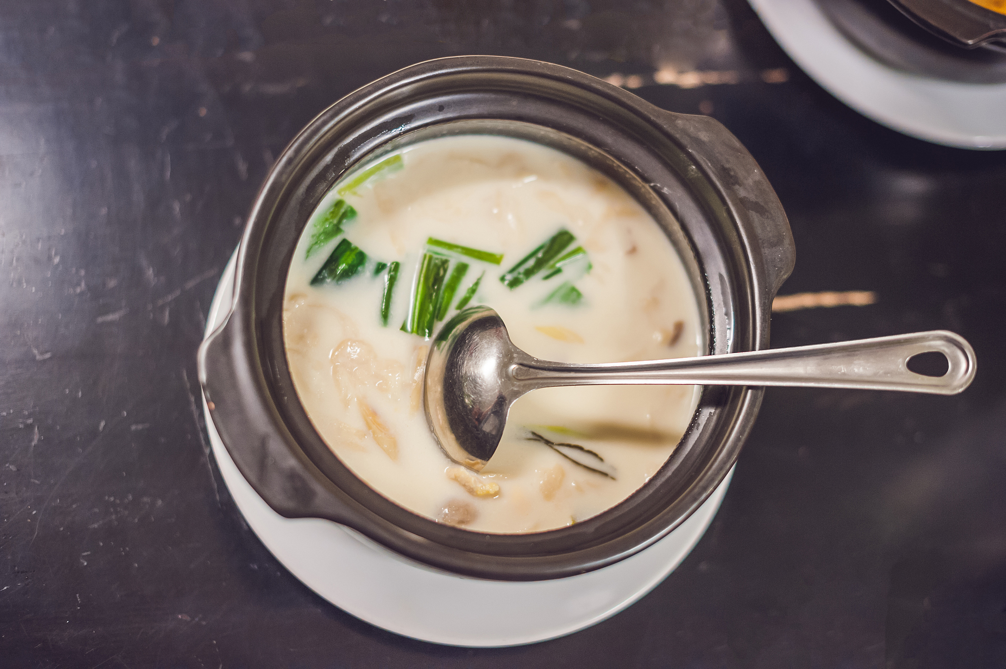 chicken and coconut milk soup on an old rustic wooden table top 