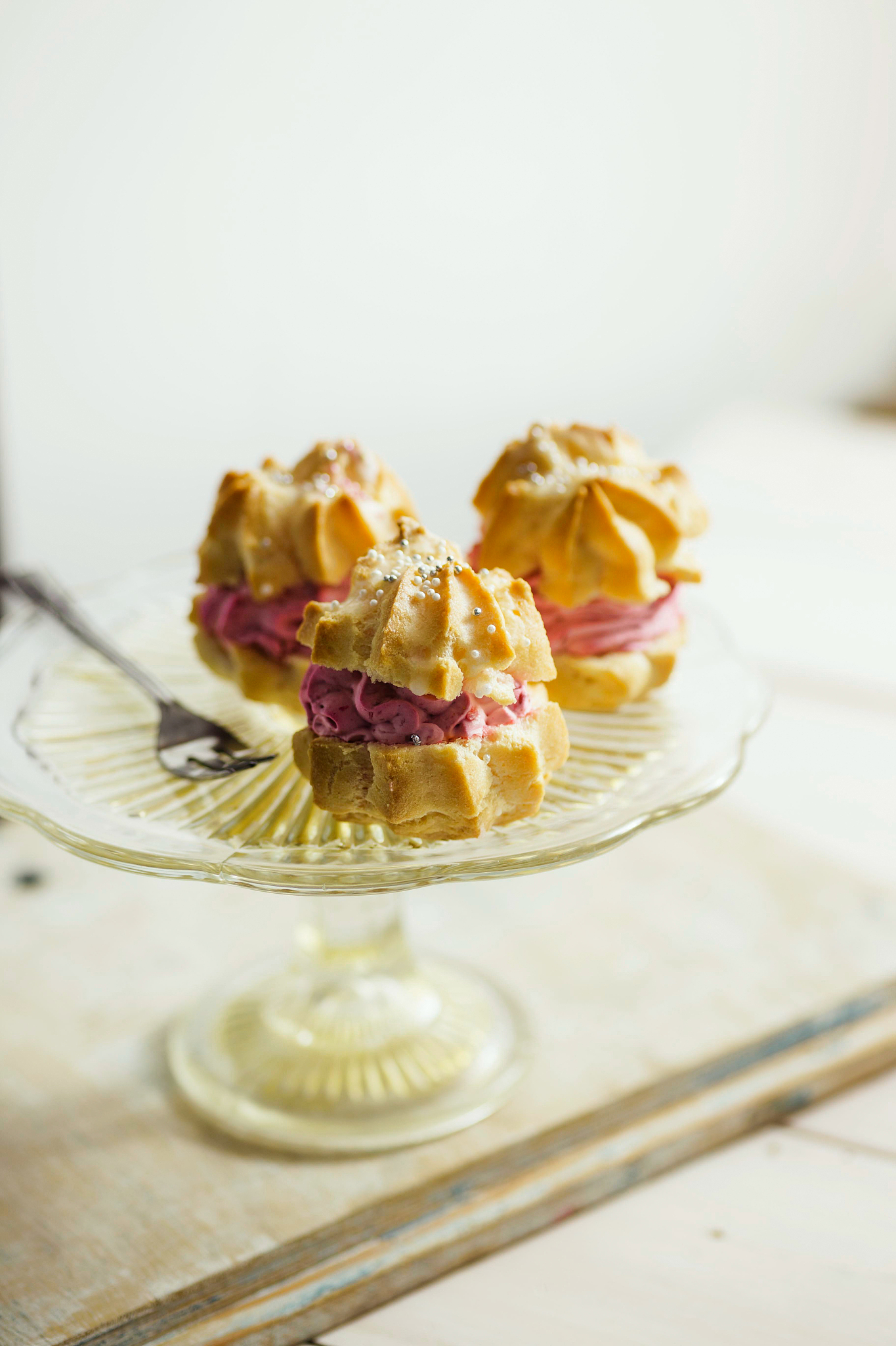strawberry cream puffs on a cake plate, served with tea.