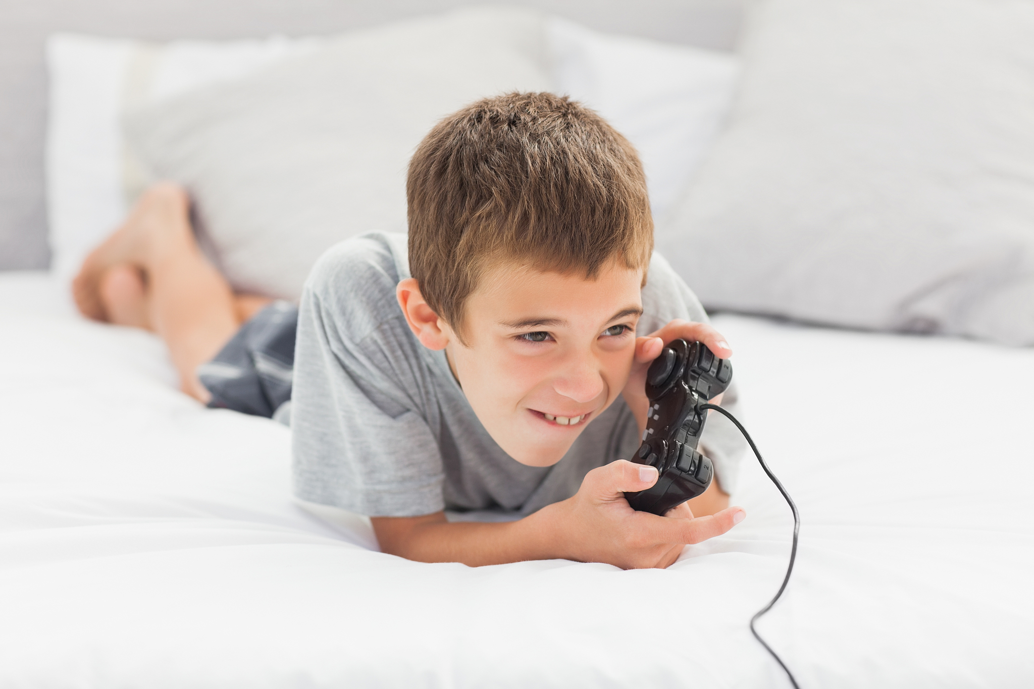 little boy lying on bed playing video games