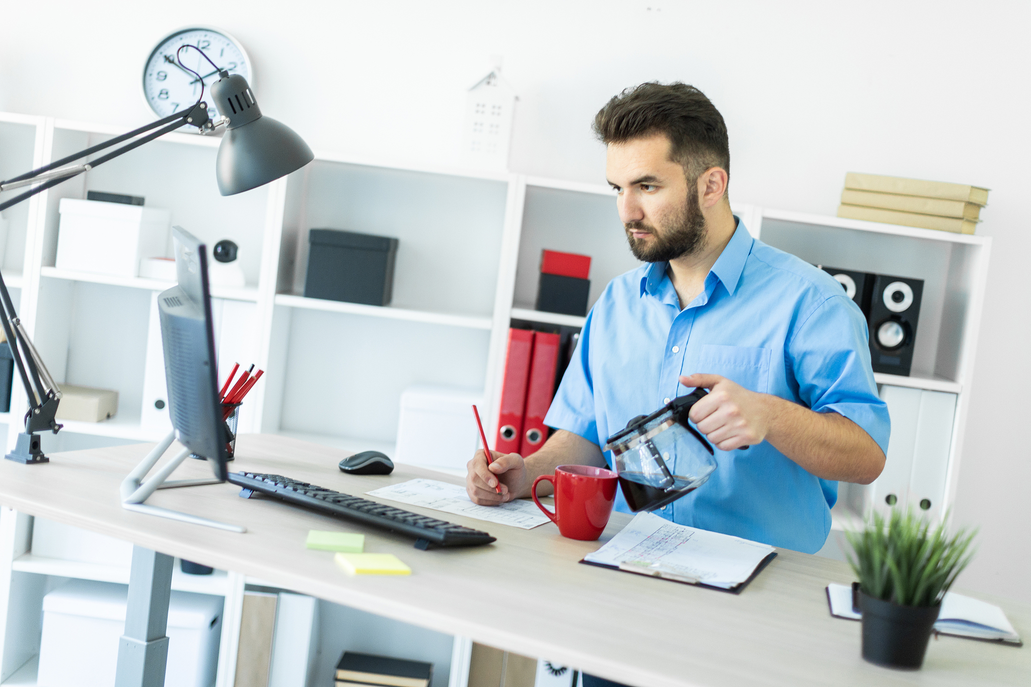 a young man stands in the office at the computer table and brews