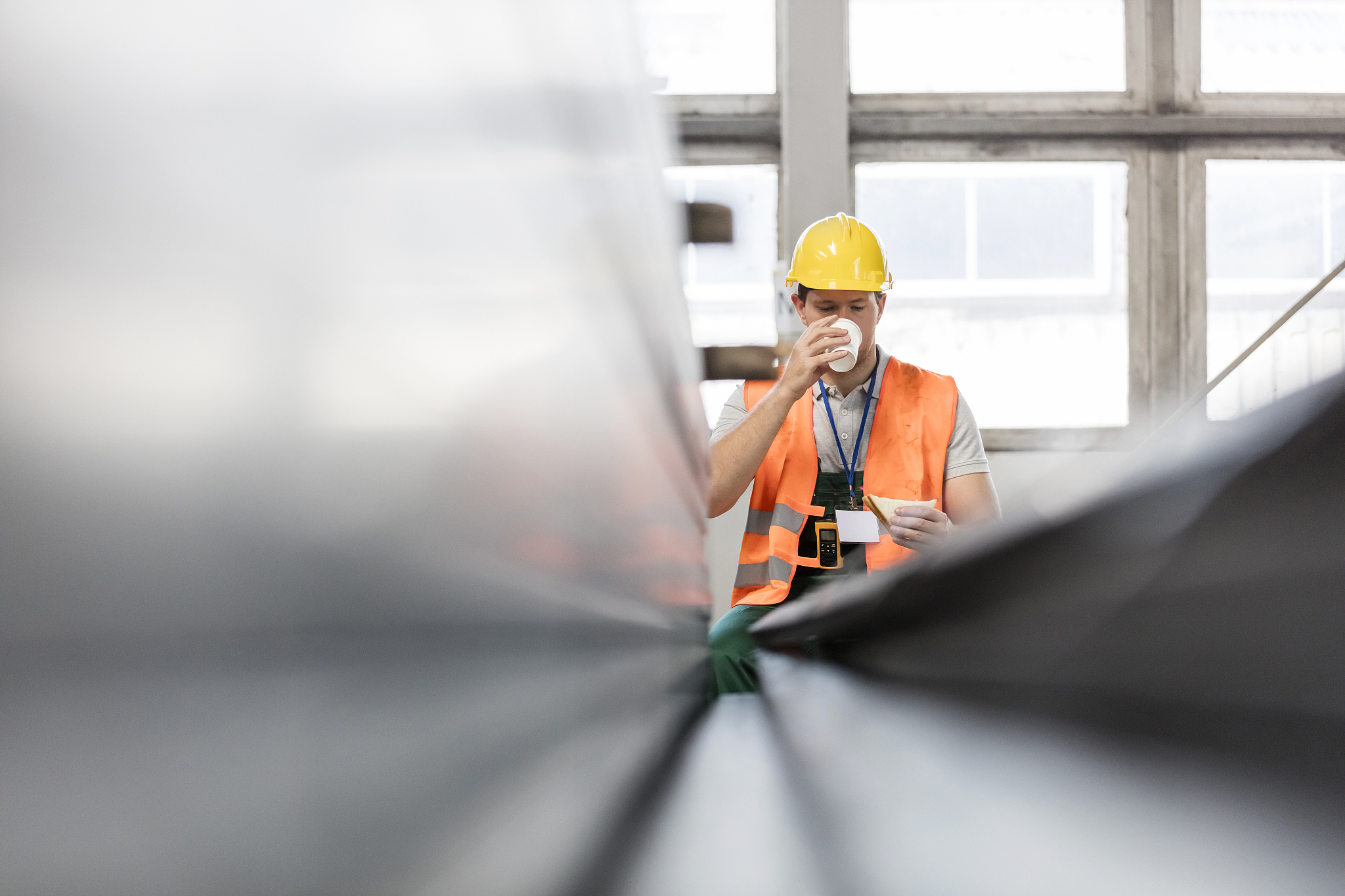 worker in protective workwear drinking coffee in factory
