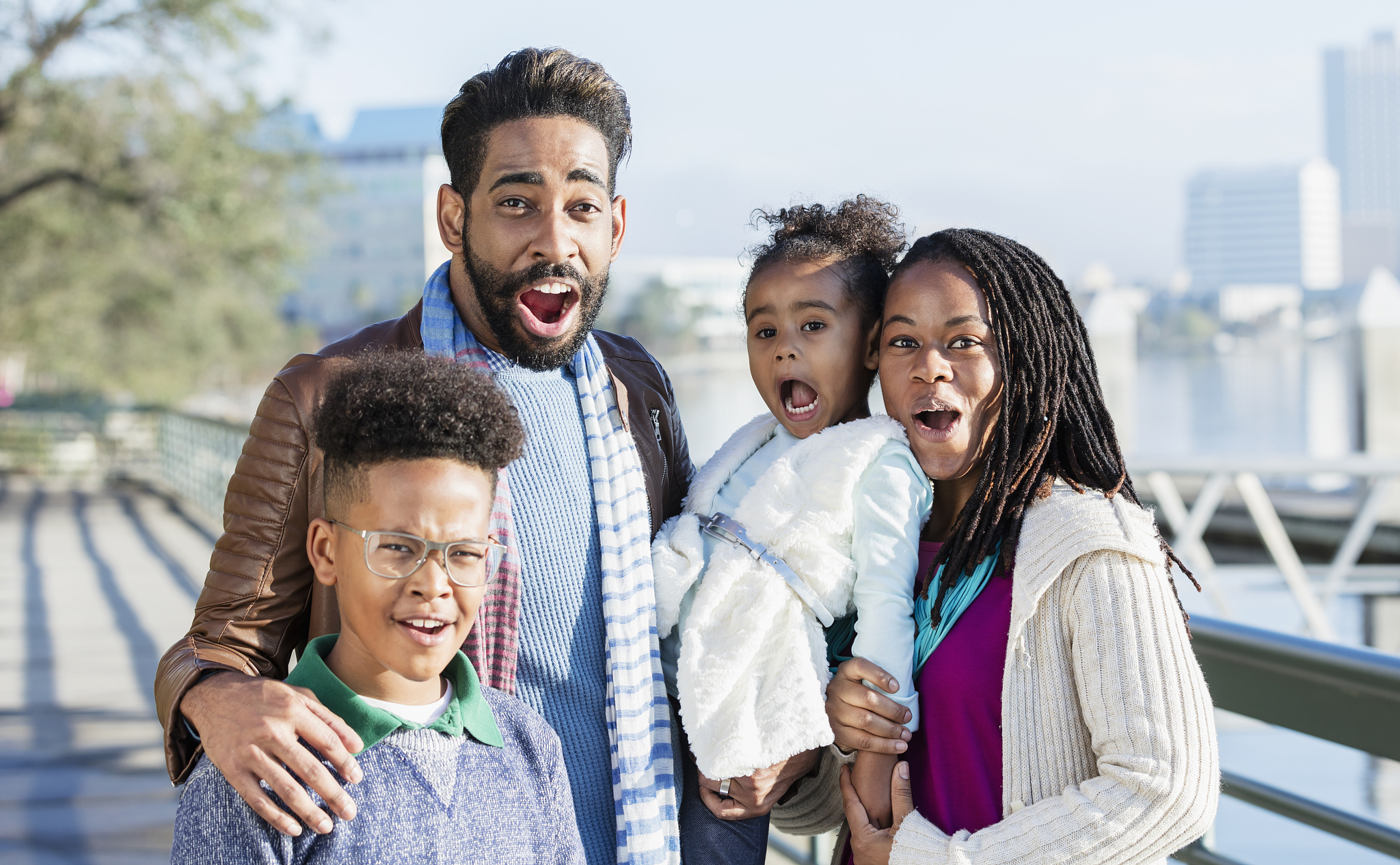 family with two children standing on city waterfront