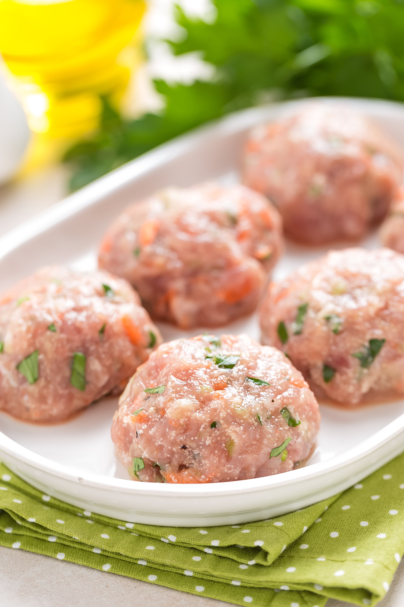 raw meatballs on white plate, cooking in kitchen