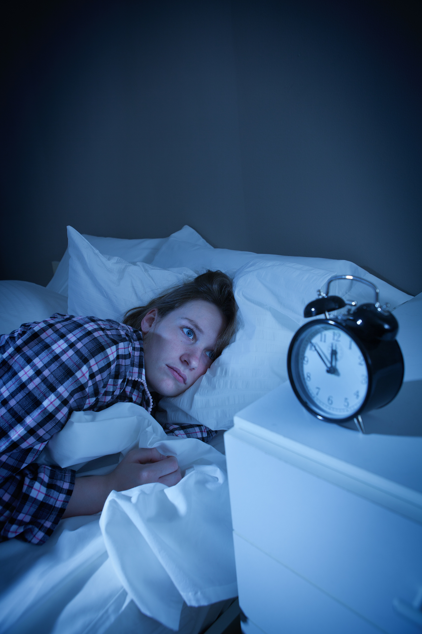 insomnia woman laying awake with alarm clock
