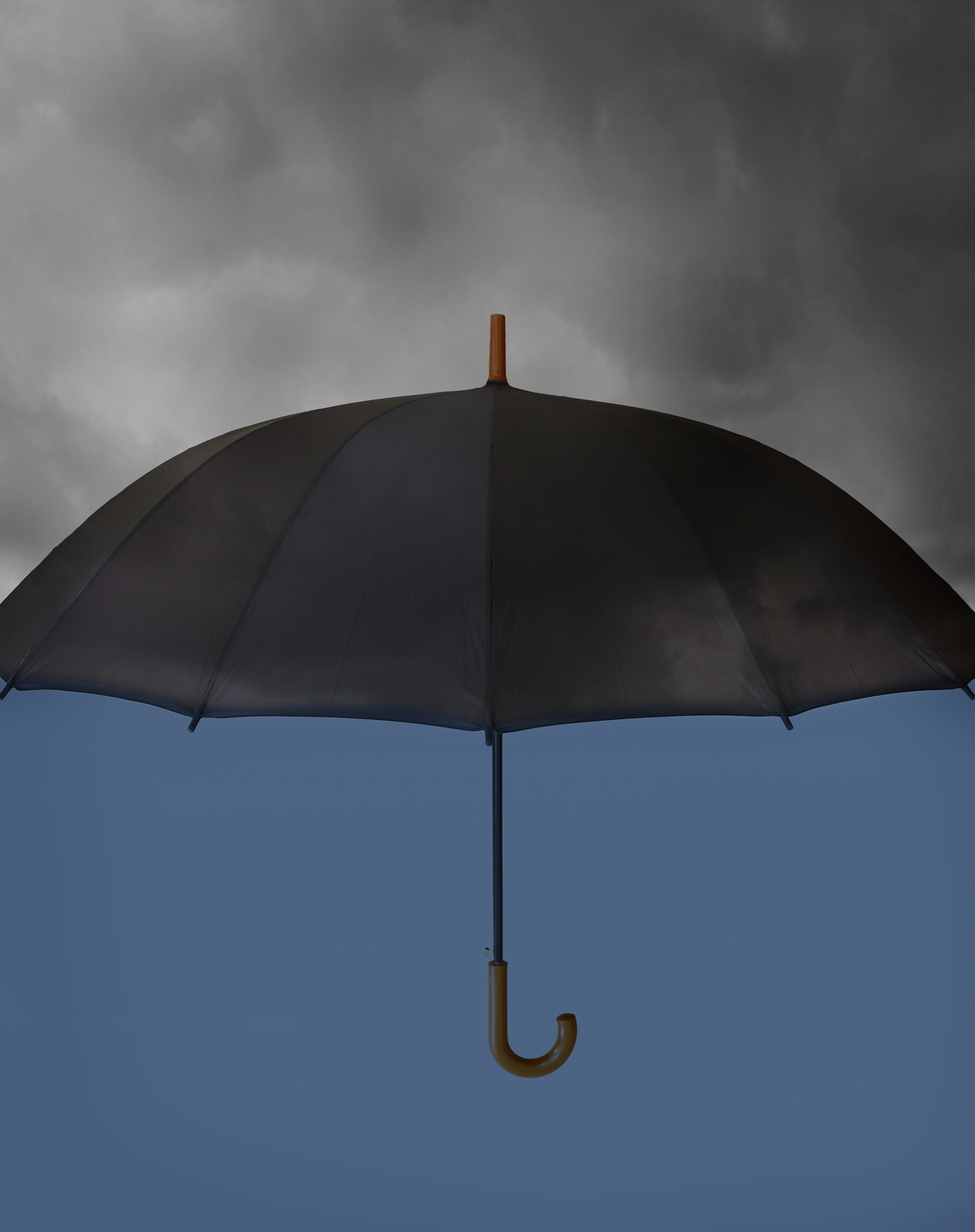 umbrella with heavy clouds above and clear blue under