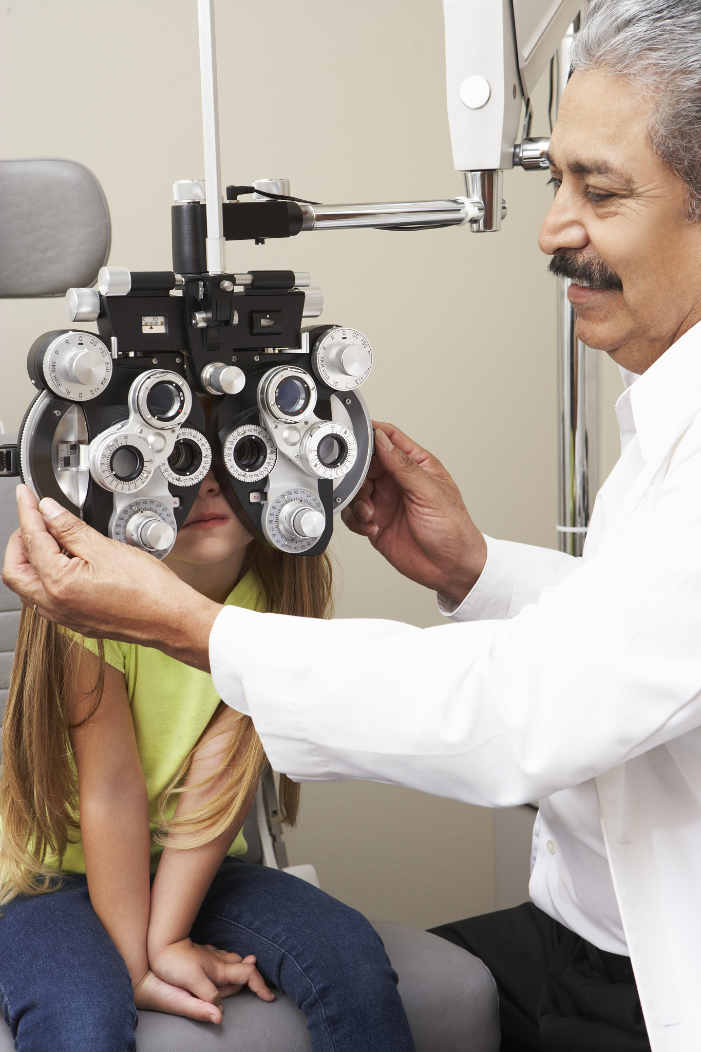 optician in surgery giving girl eye test