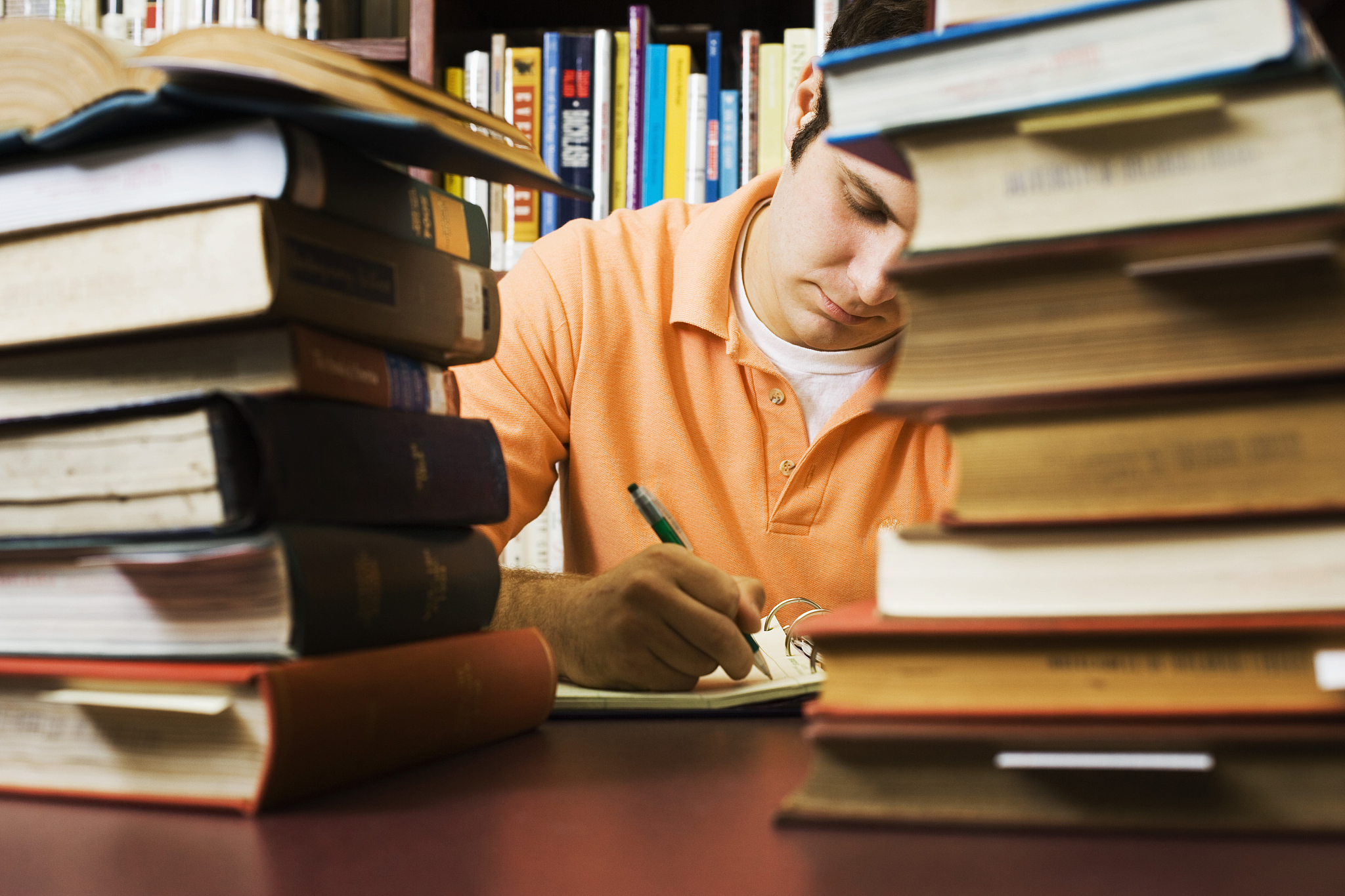student in library writing paper