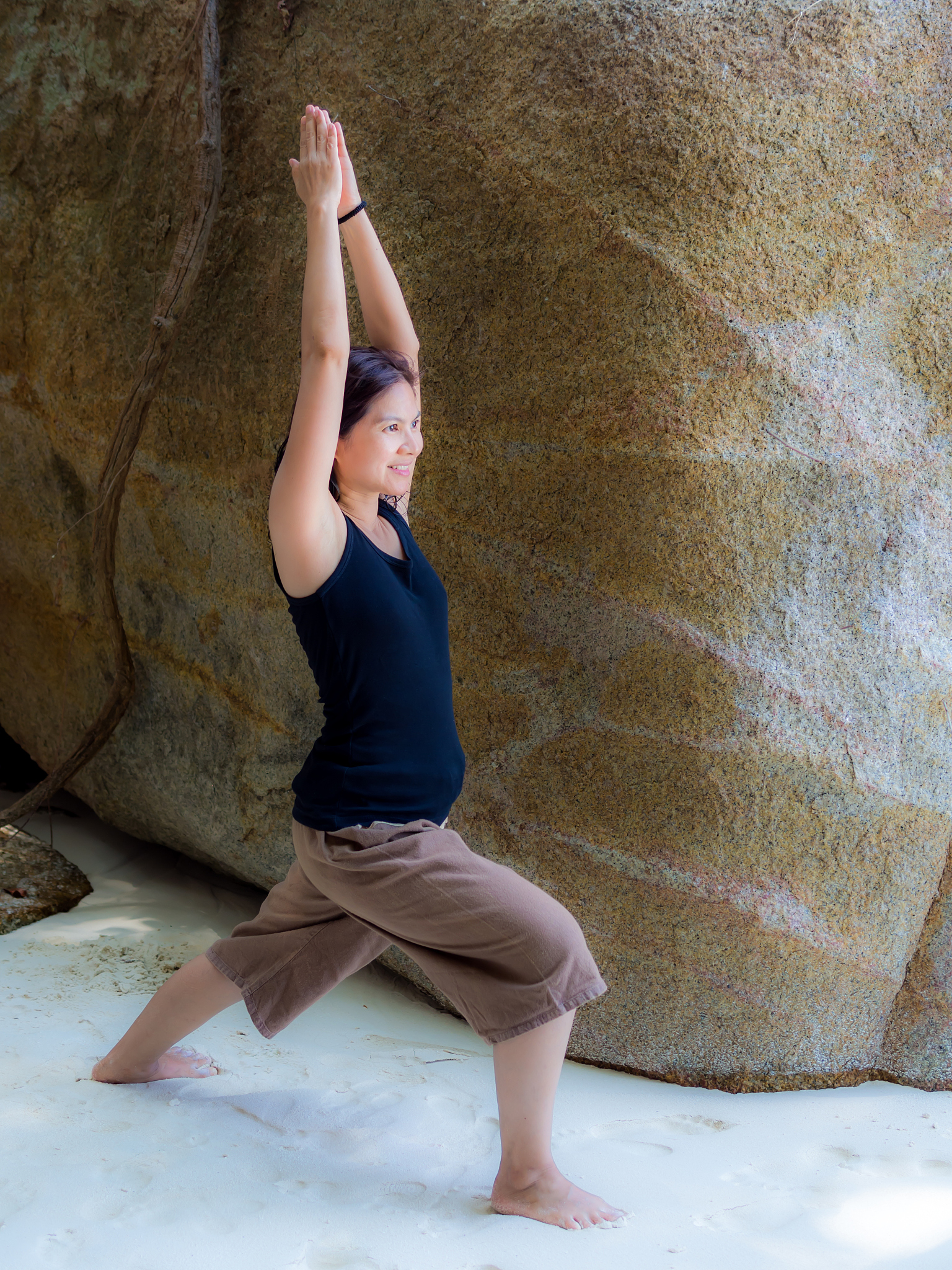 beautiful asian woman doing yoga warrior pose at the beach