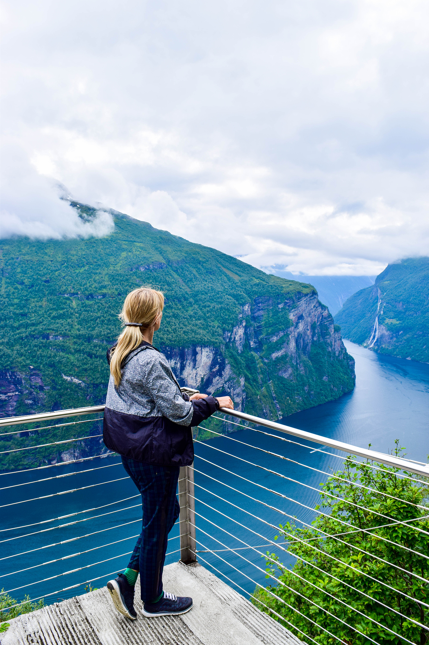 tourist woman looks at geirangerfjord and seven sisters waterfal