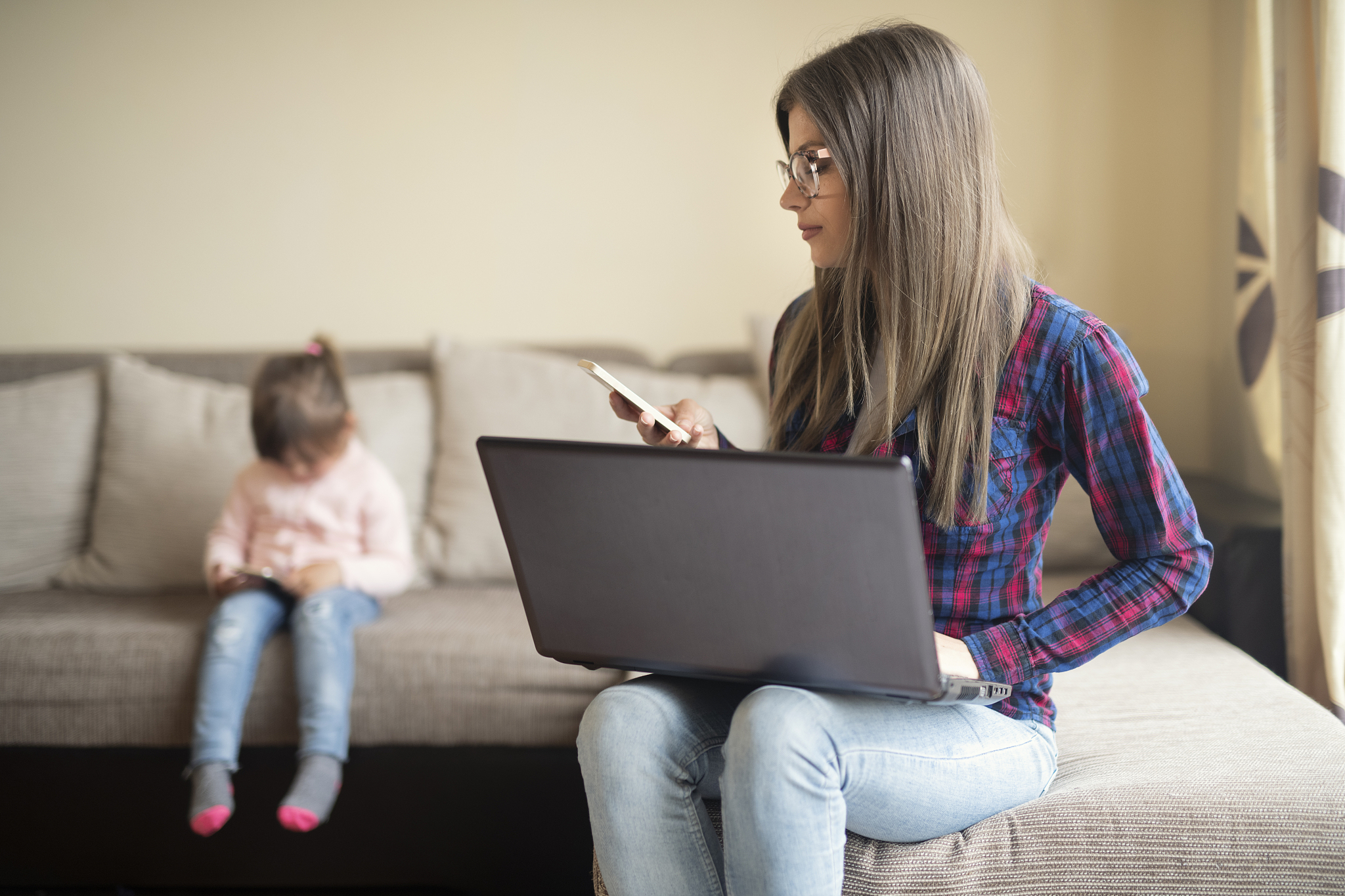 a young mother working from home, woman using phone and laptop