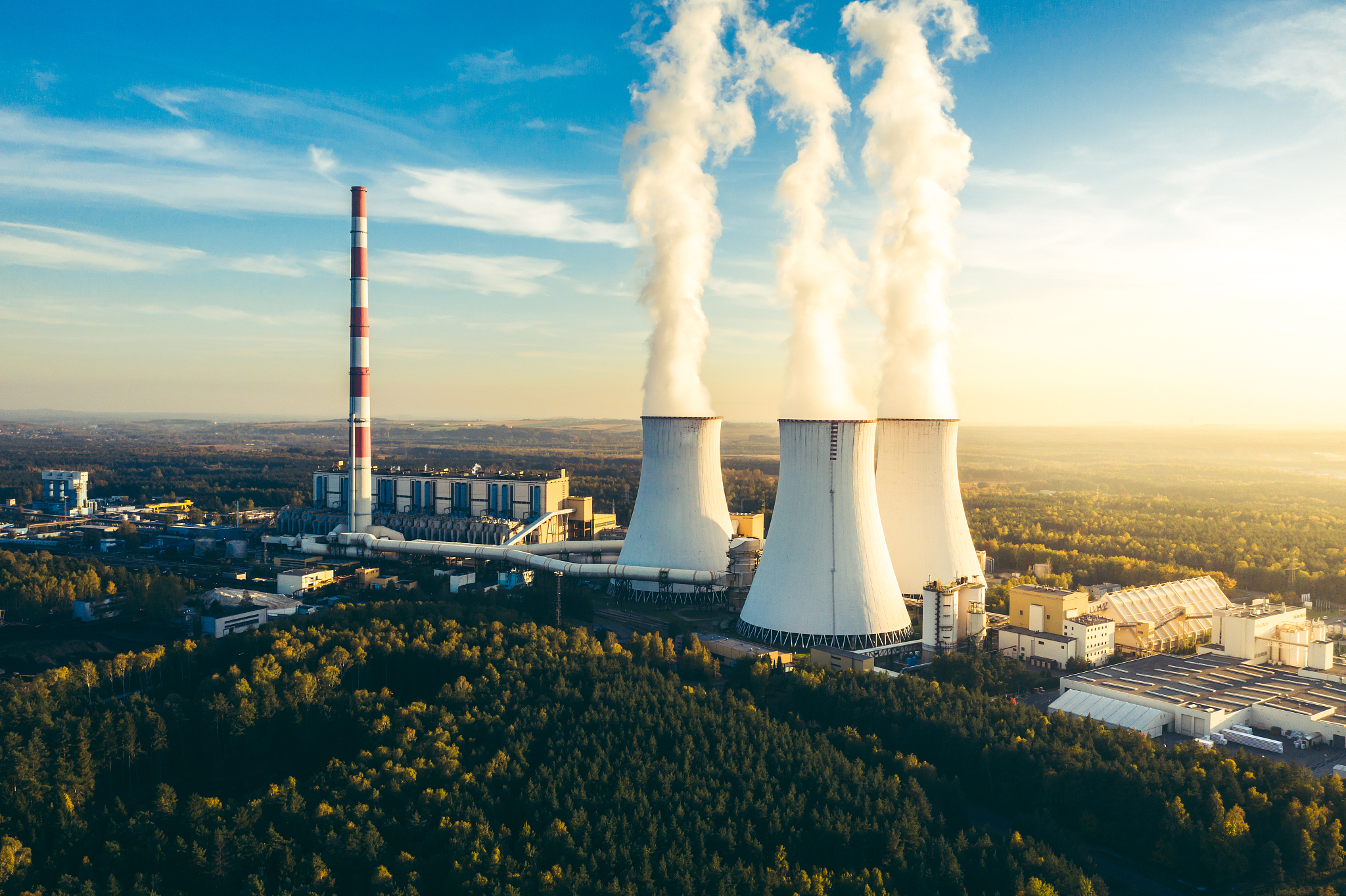 a power plant with white smoke over it's chimneys