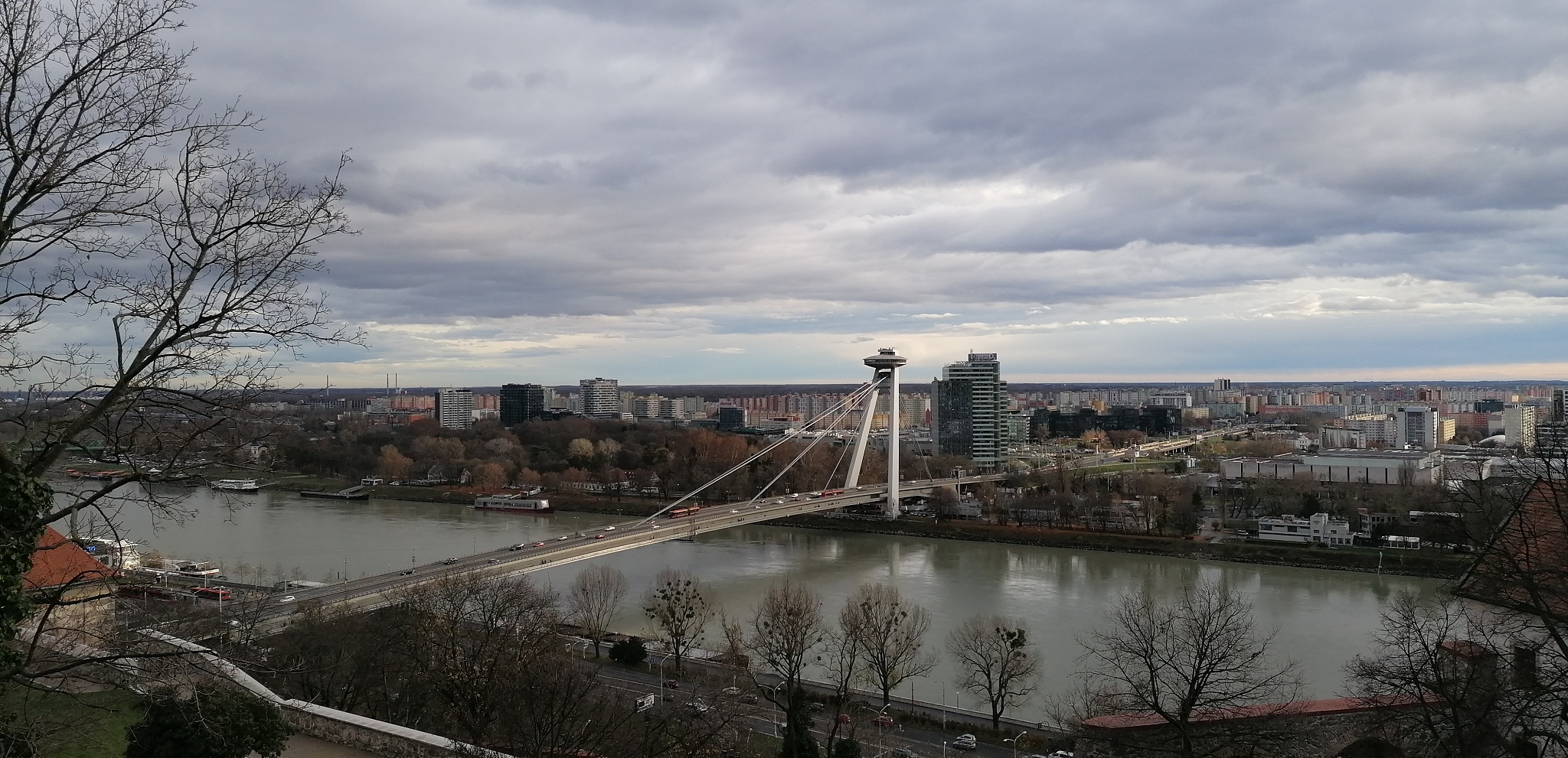 bridge over river by buildings in city against sky