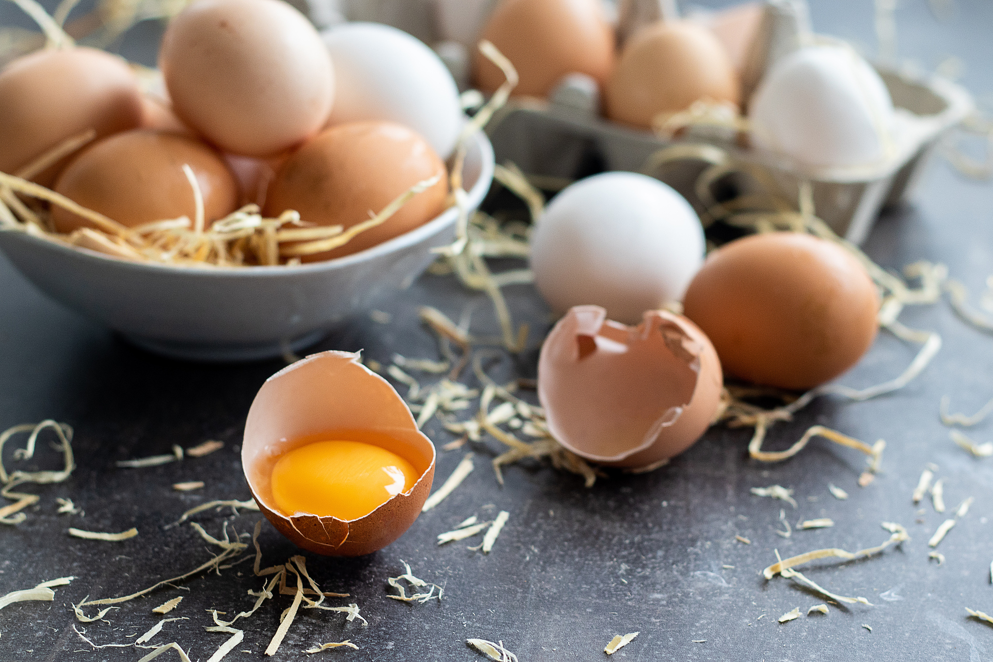 fresh organic raw eggs, white, beige and brown, one is cracked