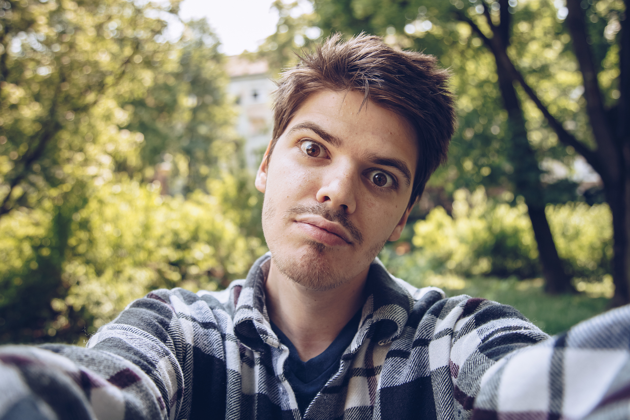 handsome young man making a silly face and taking a selfie photo