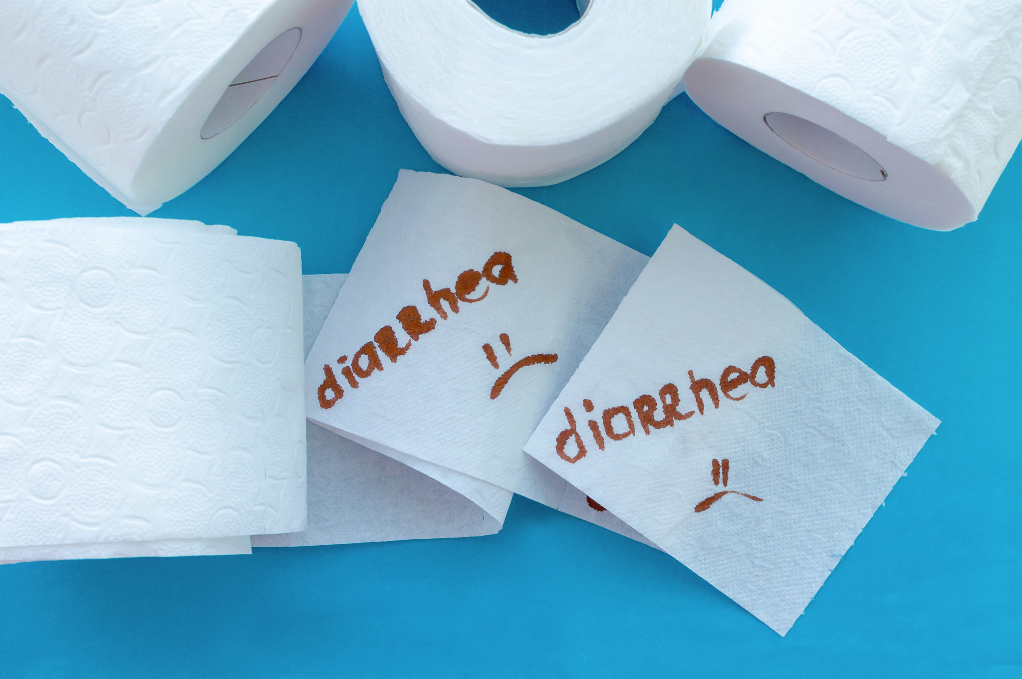 rolls of white toilet paper labeled "diarrhea" on a blue backgro