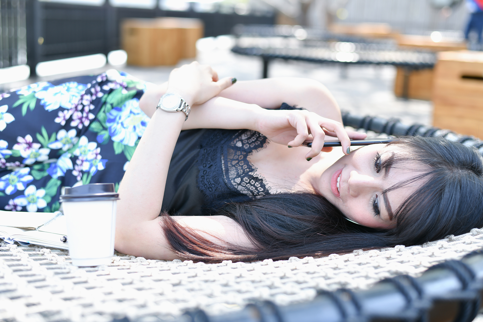 young <strong>w</strong>oman talking over smart phone while lying outdoors
