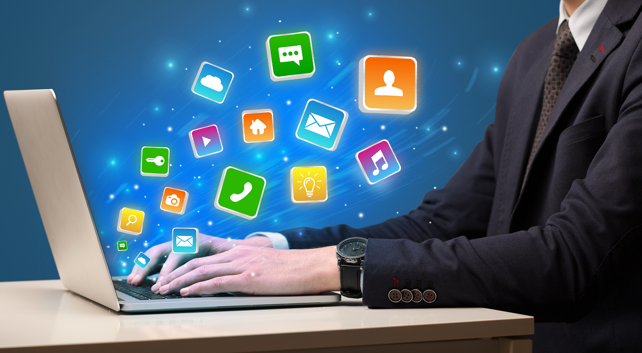 hand using laptop with application icons flying around