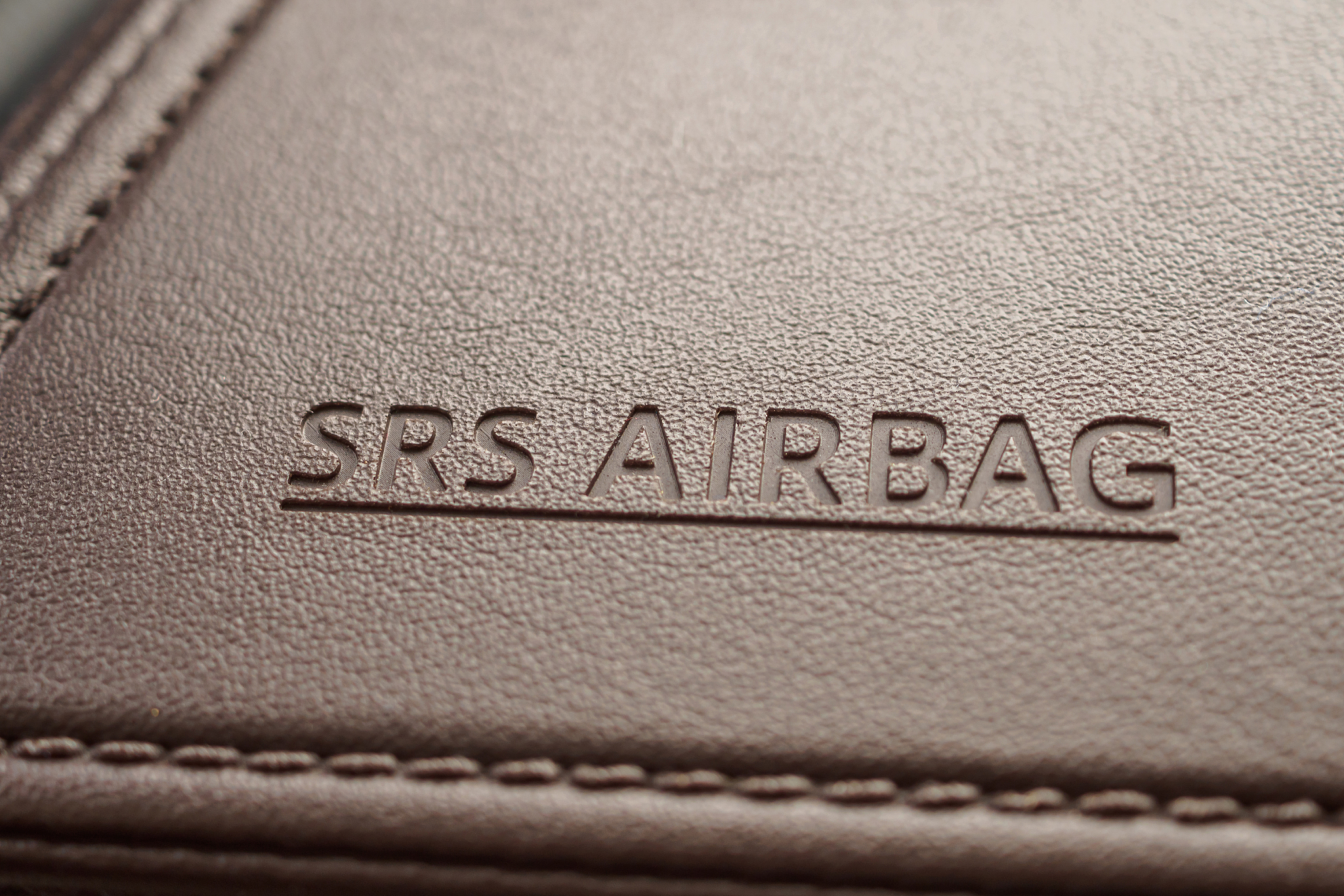 airbag safety sign on brown leather texture in modern car