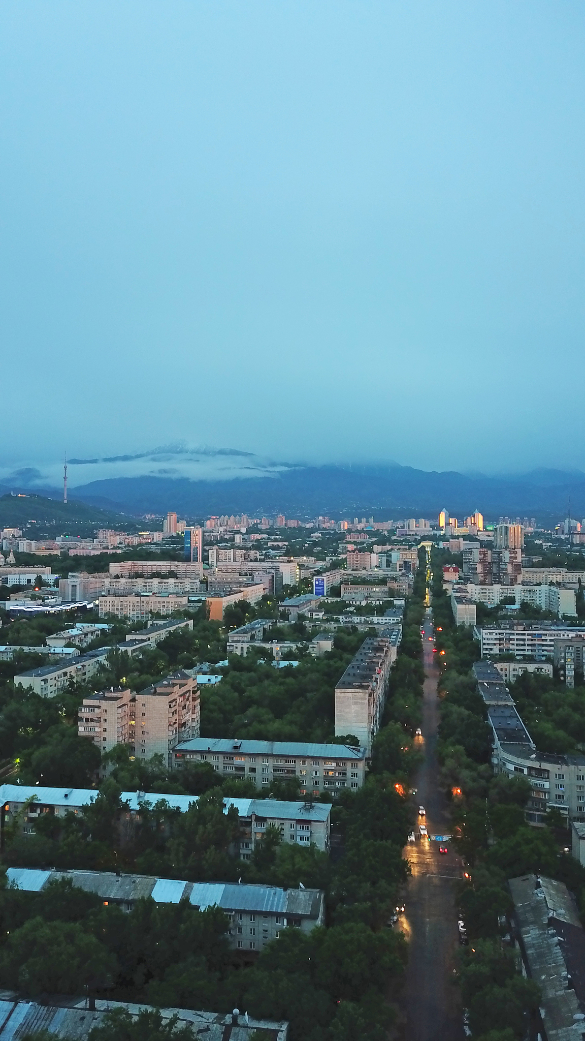 clouds over mountains and city of almaty at sunset