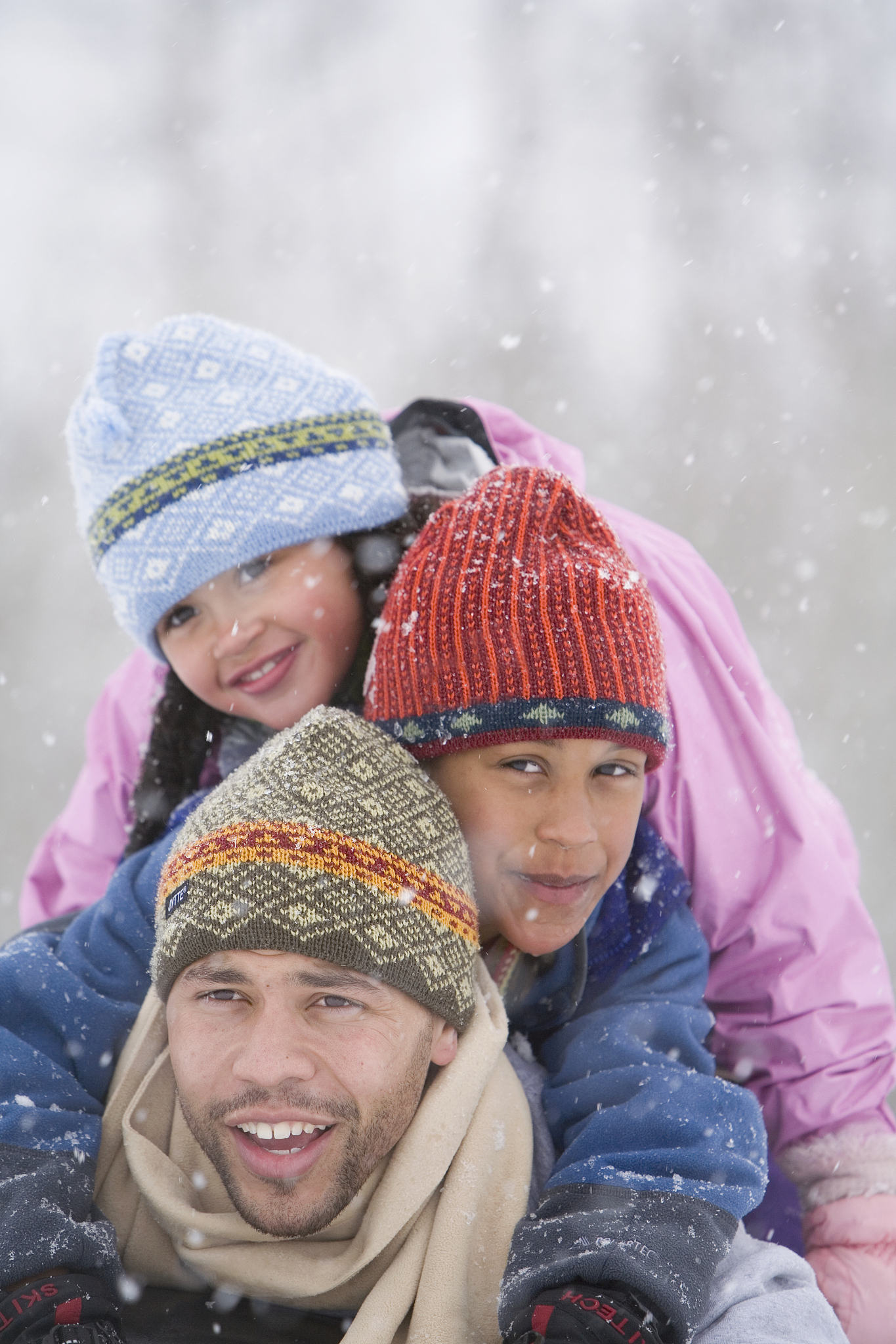 father and two children (6-8) playing in snow, portrait, close-u