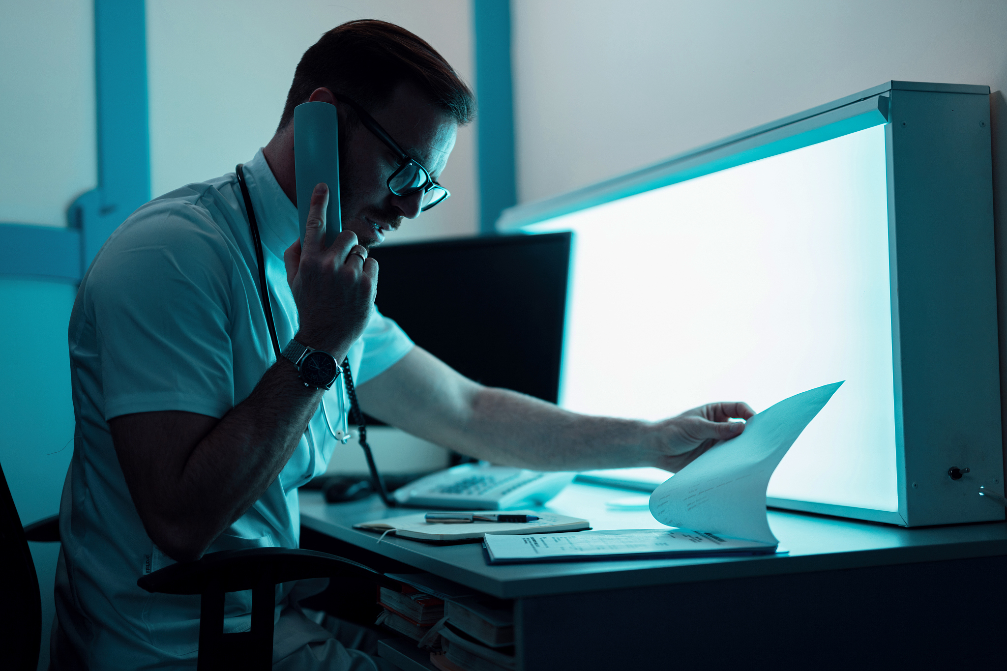 general practitioner reading medical reports while making a phon