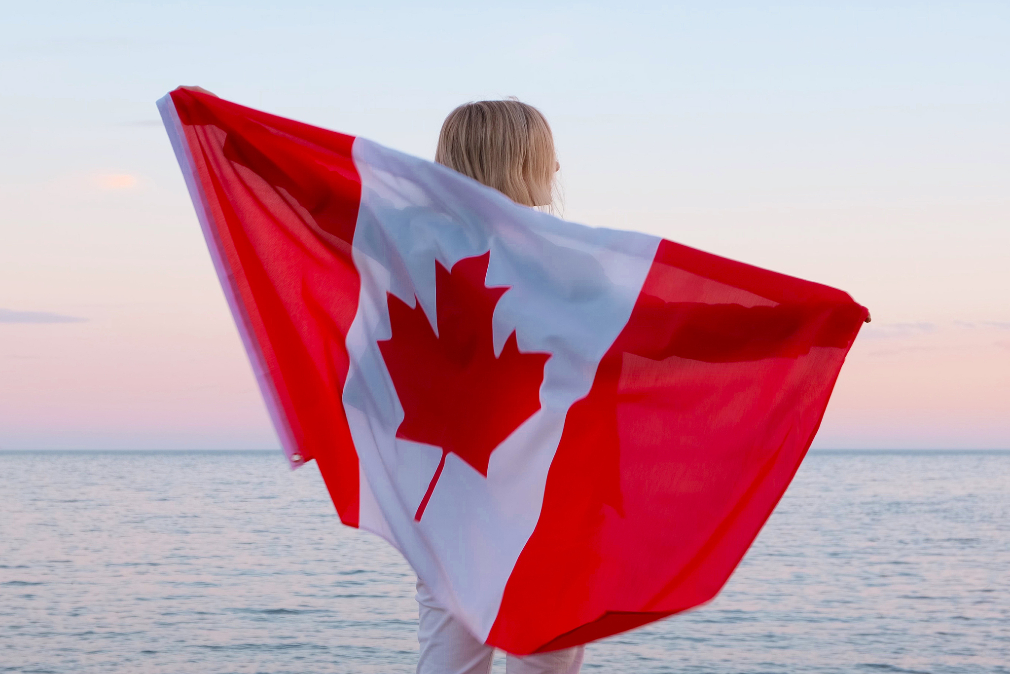 back view woman waving national canada flag outdoors ocean sea s