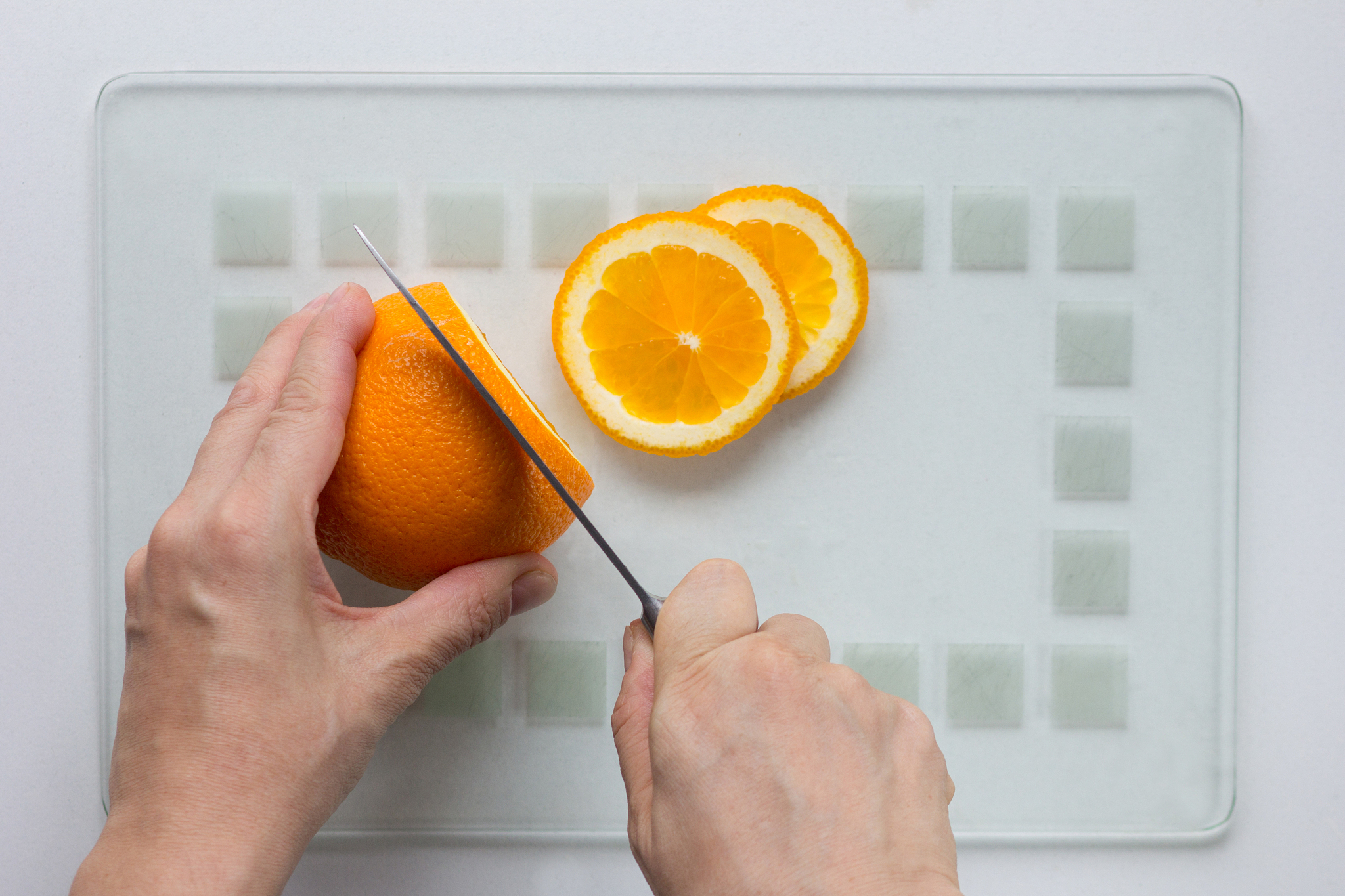 woman hand cut orange with knife on white background