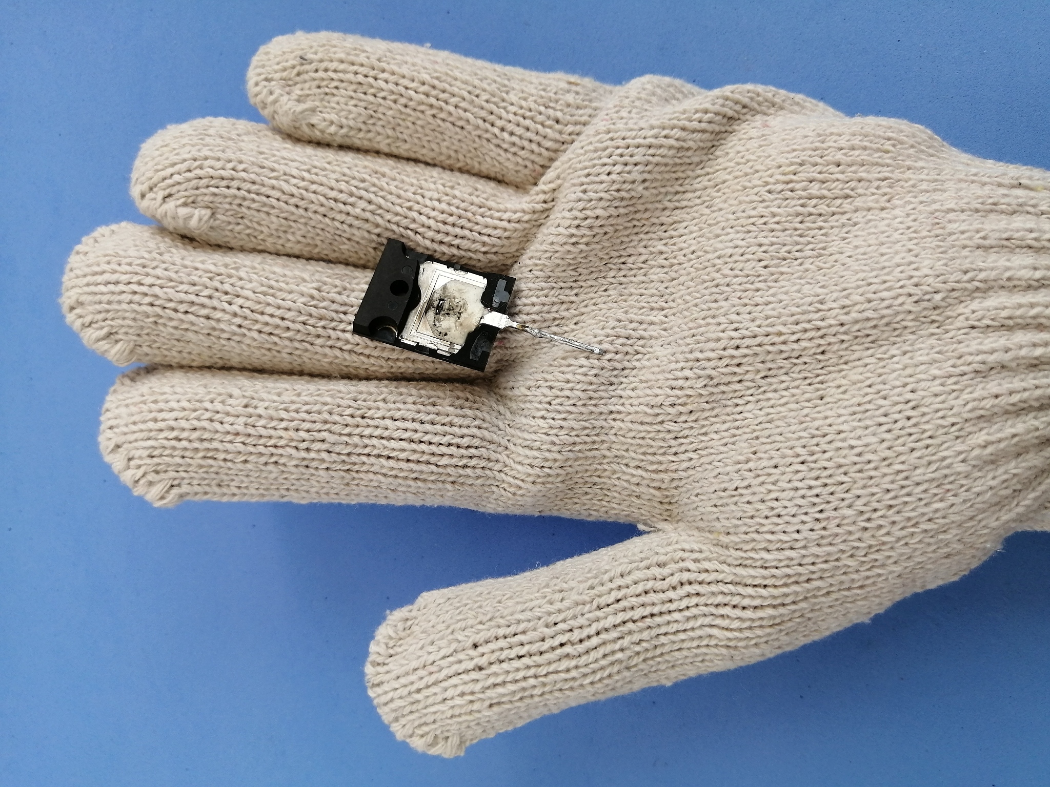 part of a broken transistor on a gloved hand