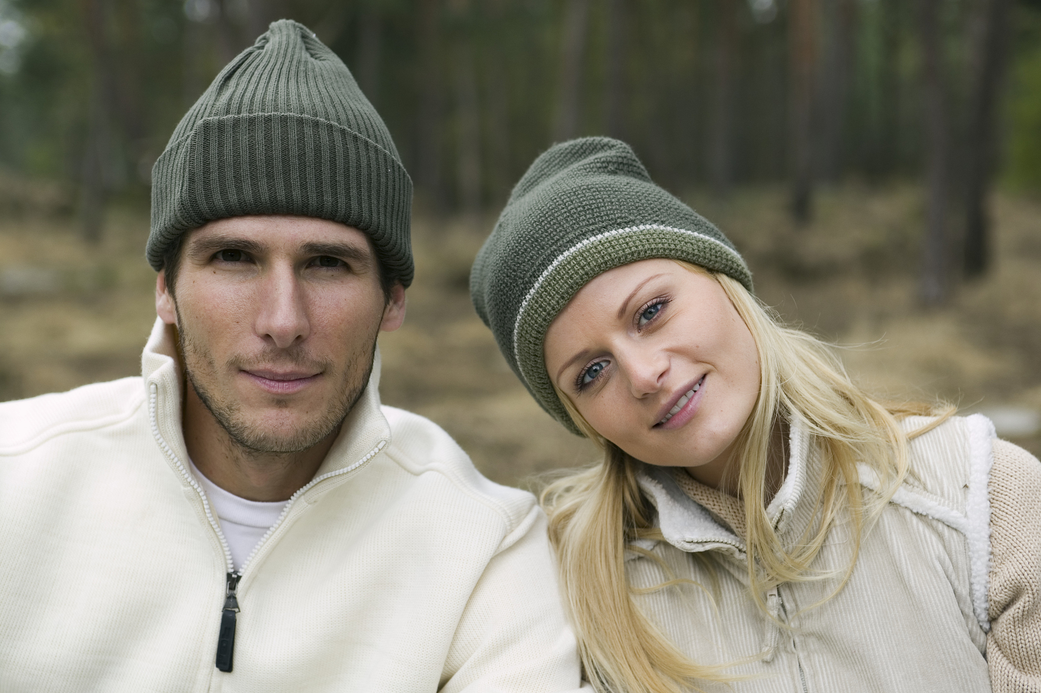 couple wearing woolly hats outdoors, smiling, portrait