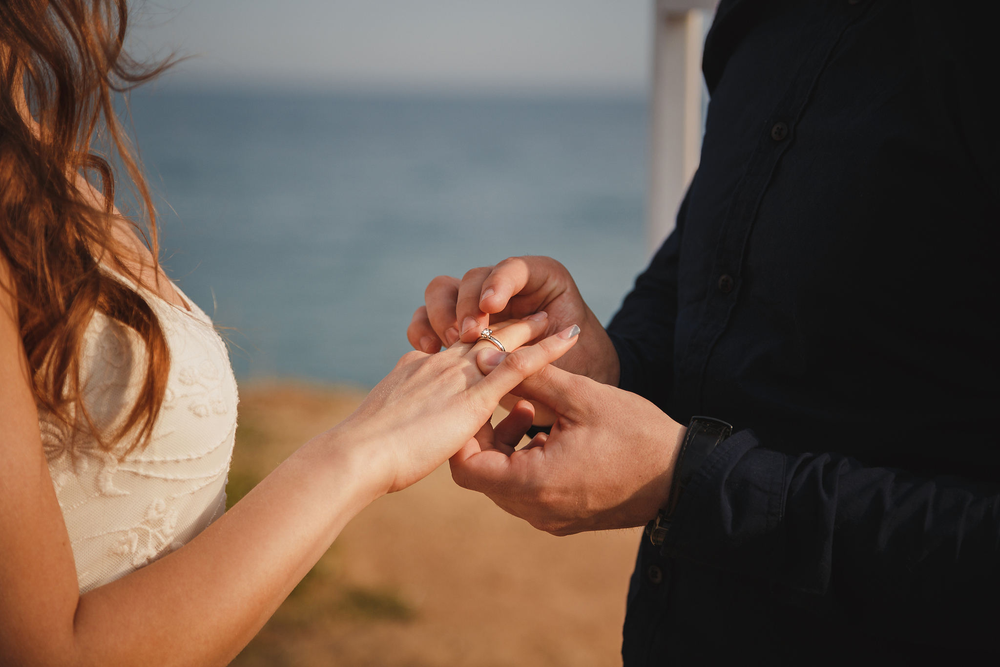 man is putting wedding ring on his bride's hand, close up. outdo