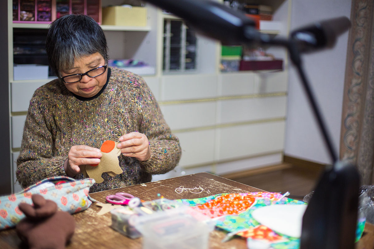 一位年长妇女在她的家中缝纫和制作工艺品