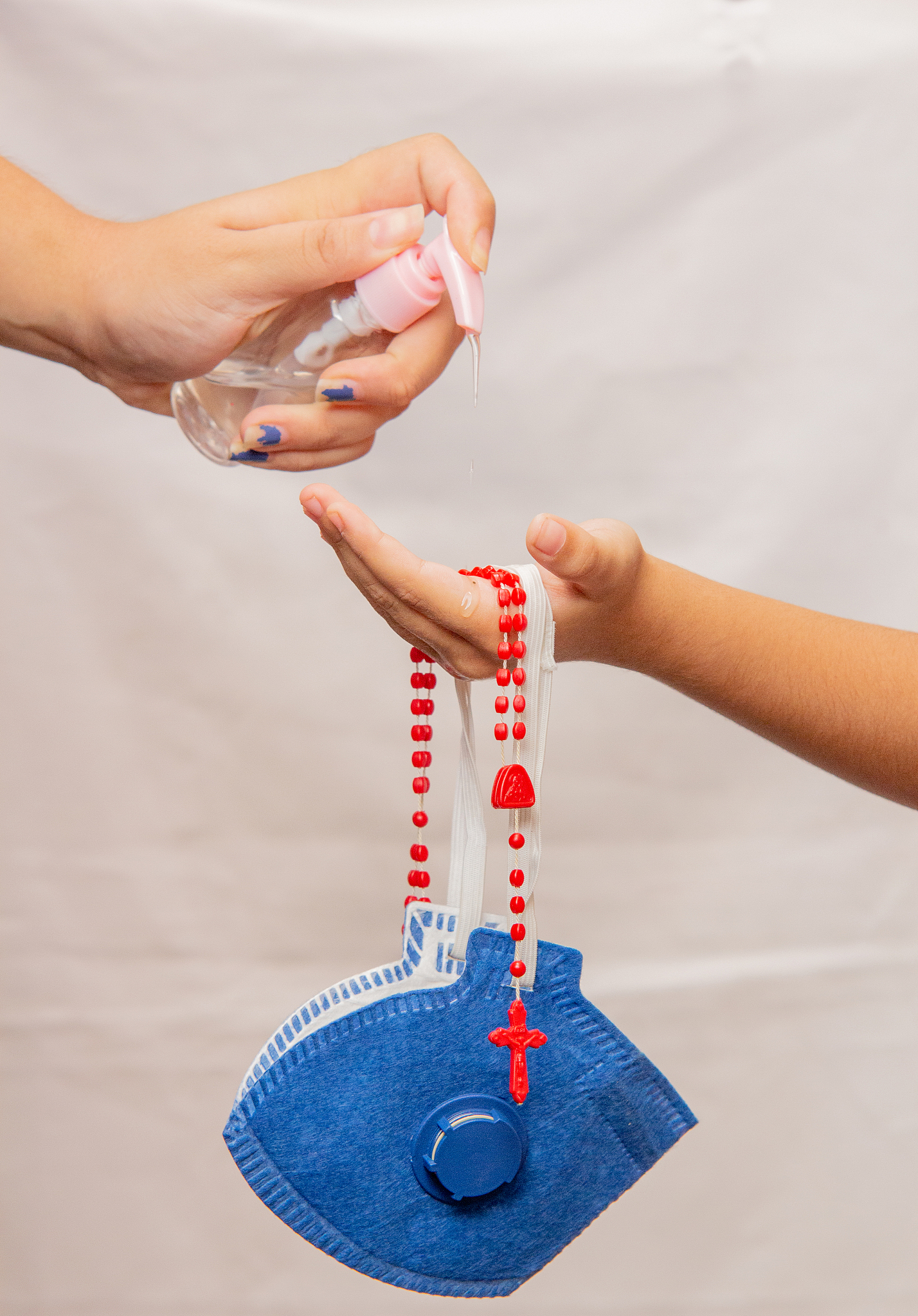 woman putting gel alcohol in child's hands, with mask and a red 