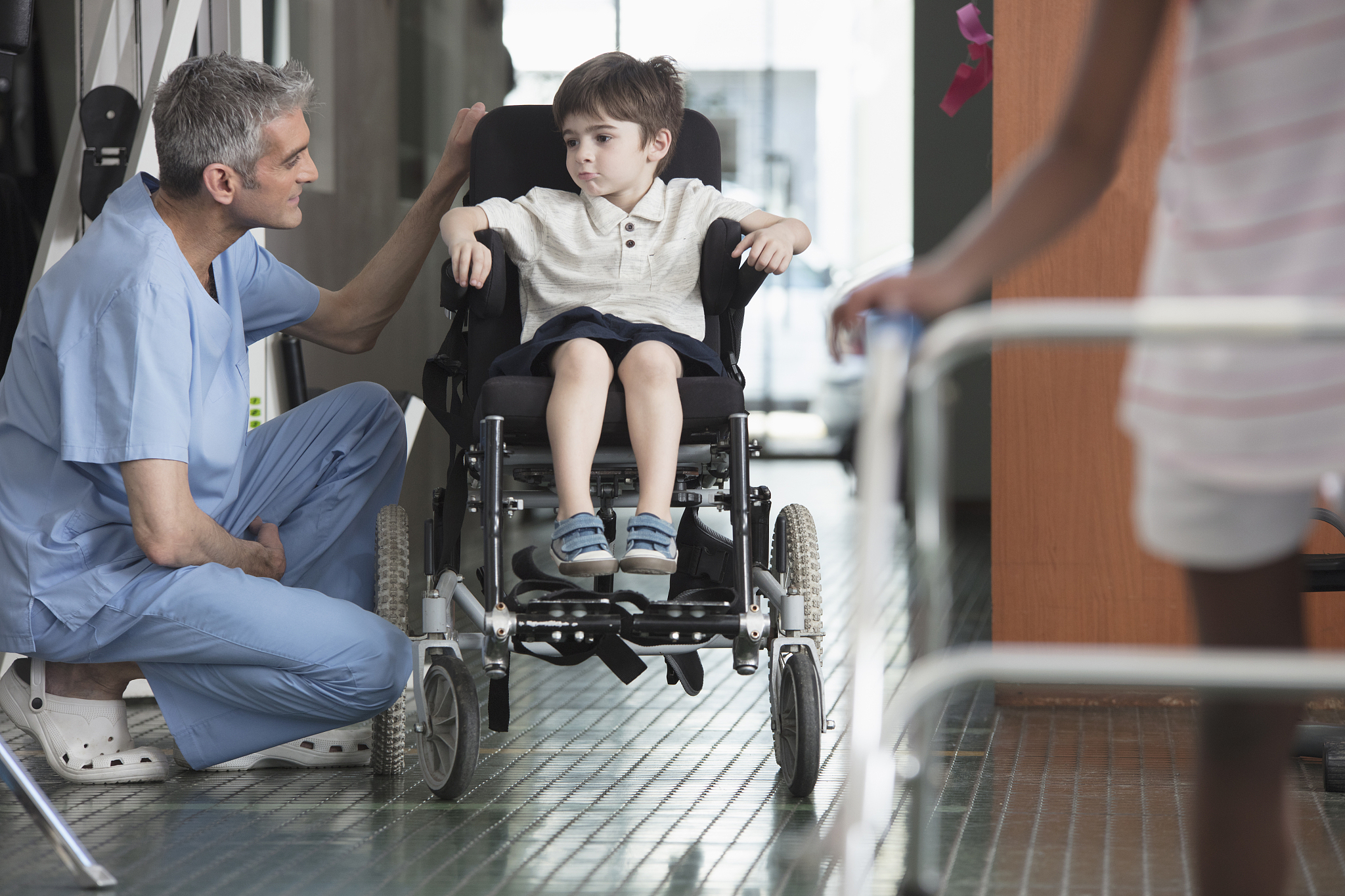 physical therapist talking to boy in wheelchair