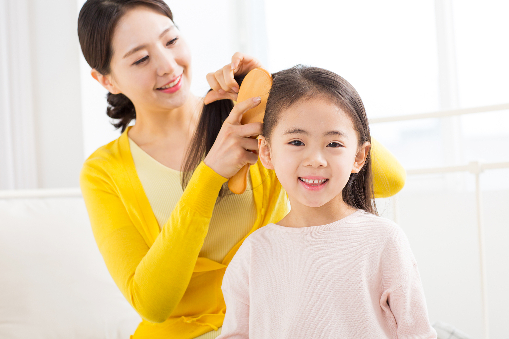 mother tying her daughters hair