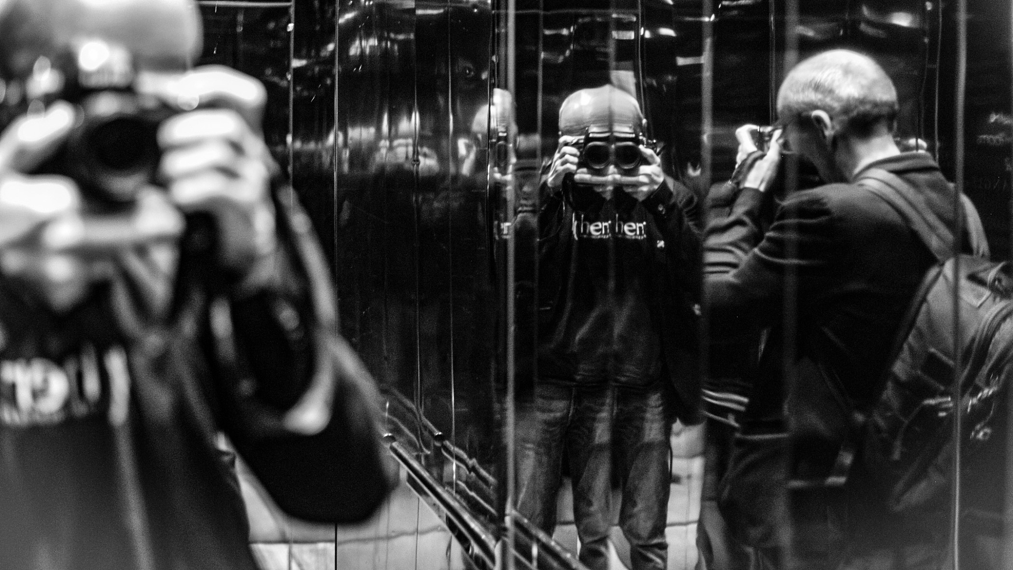 reflection of man photographing with camera on mirror