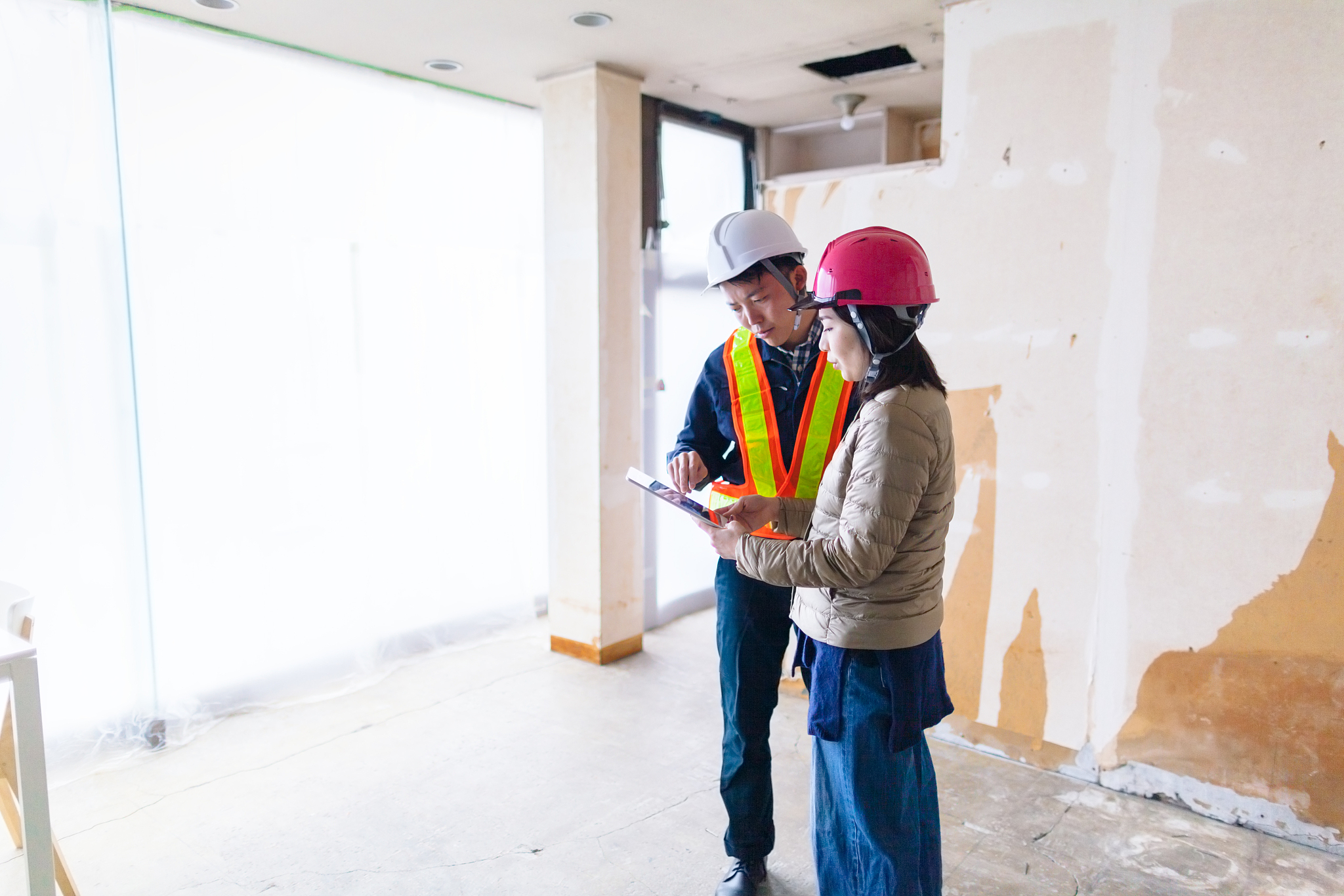 young female building contractor explaining work to male constru