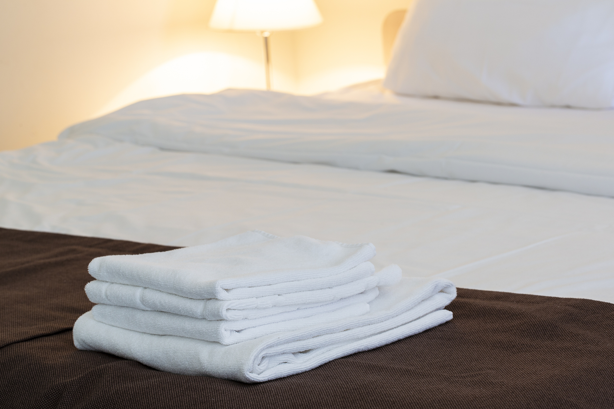 white folded towels, linen beddings on tidy bed.