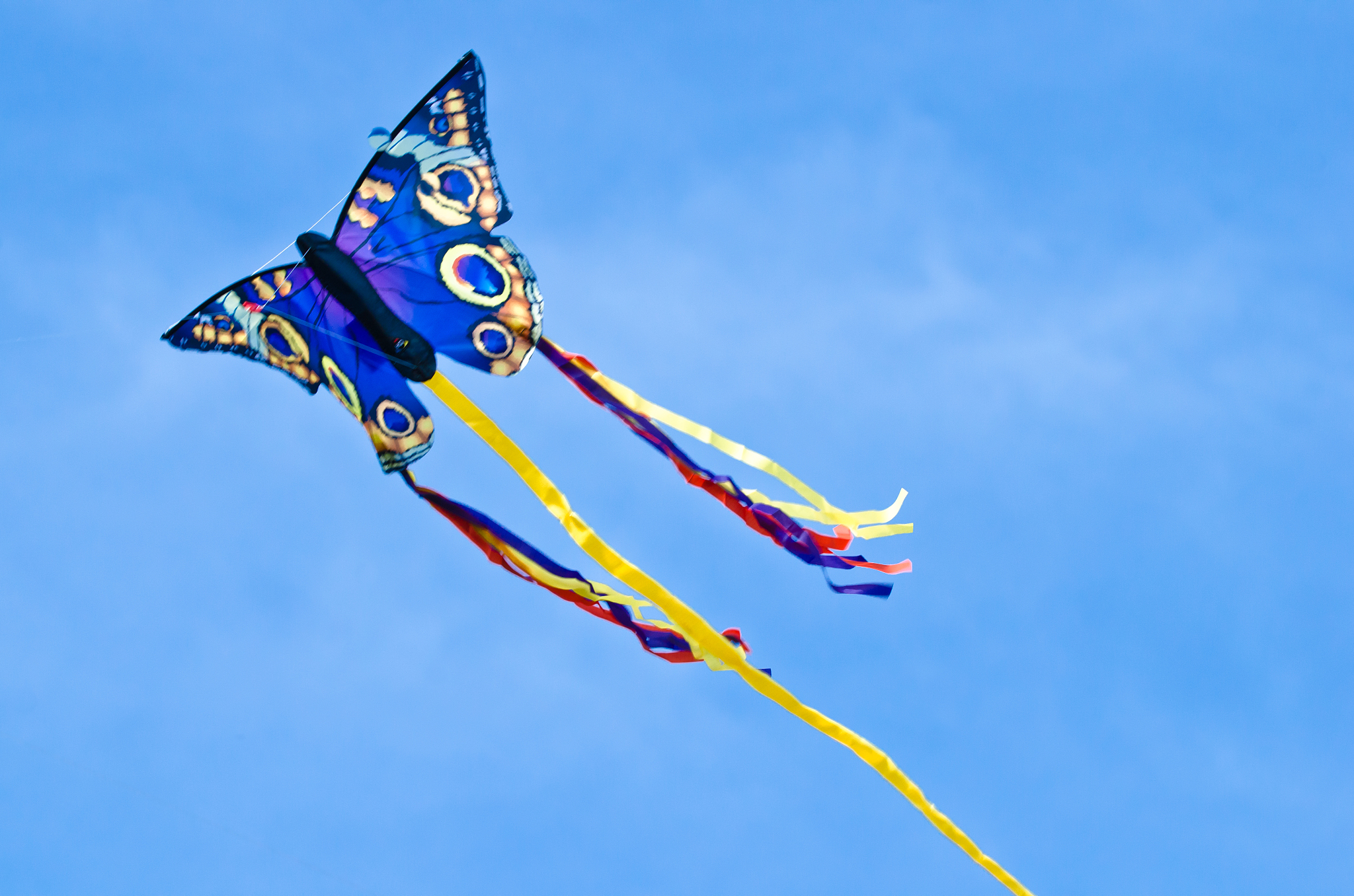 a beautiful, colourful stunt kite, in the blue sky, high up in t