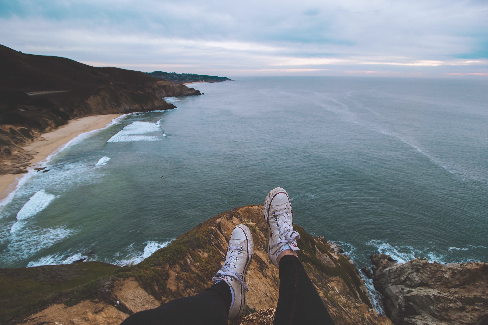 low section of person sitting on cliff against sea