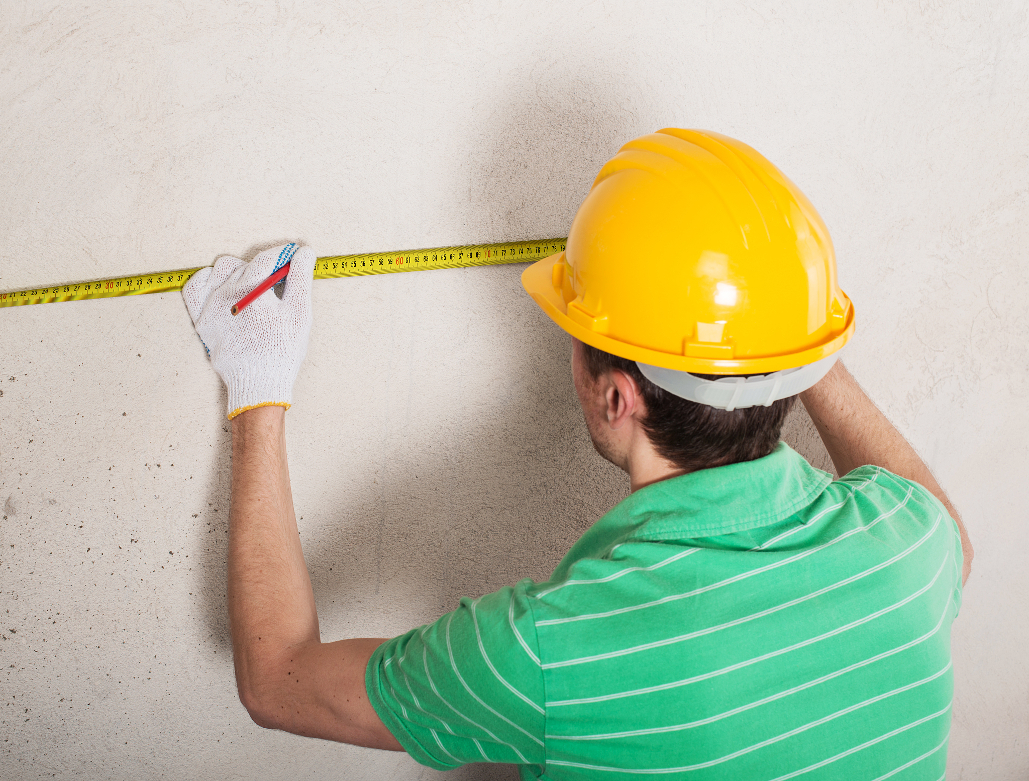 construction worker measuring plaster wall