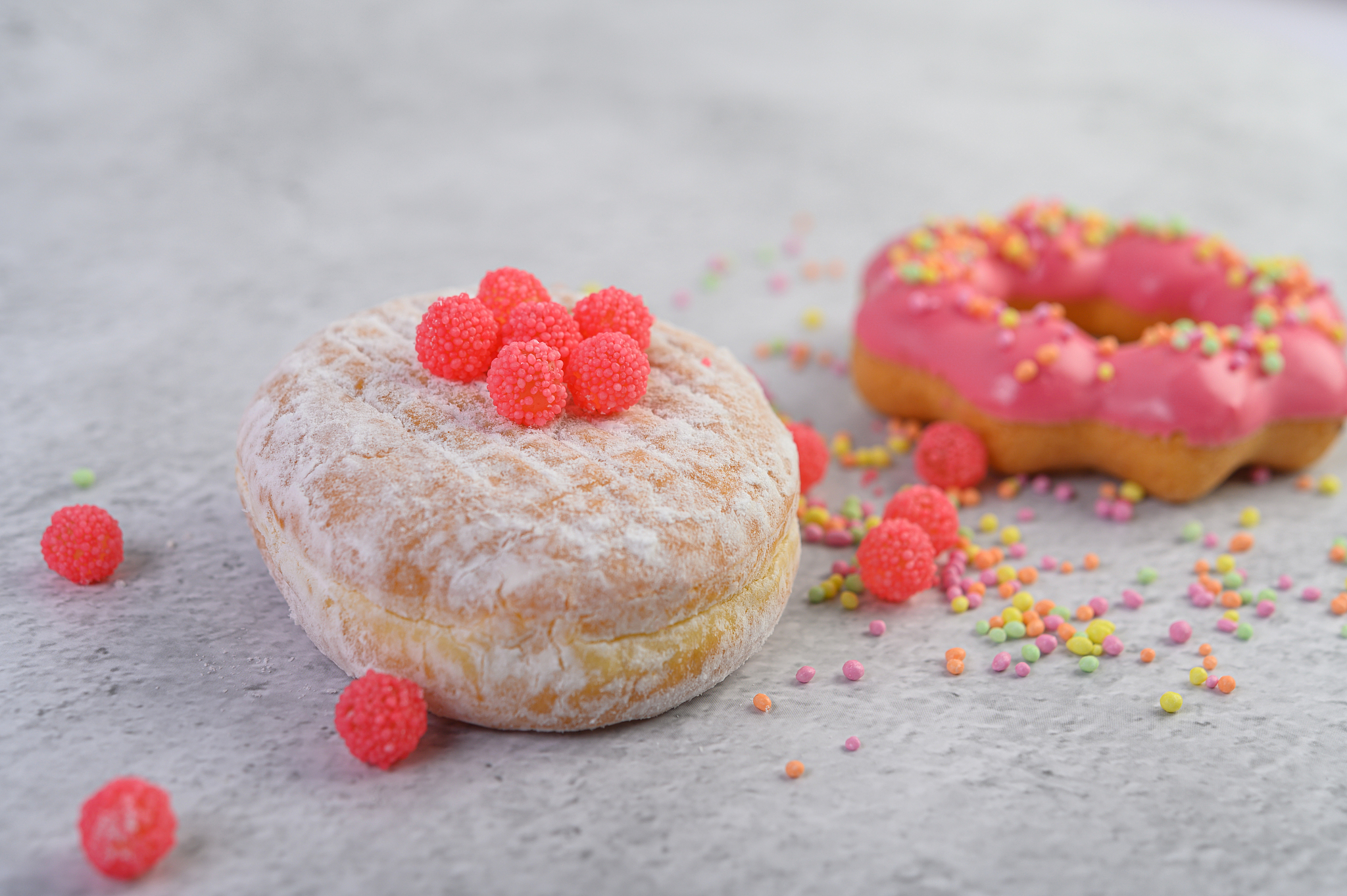 donuts sprinkled with icing sugar and candy on a white backgroun