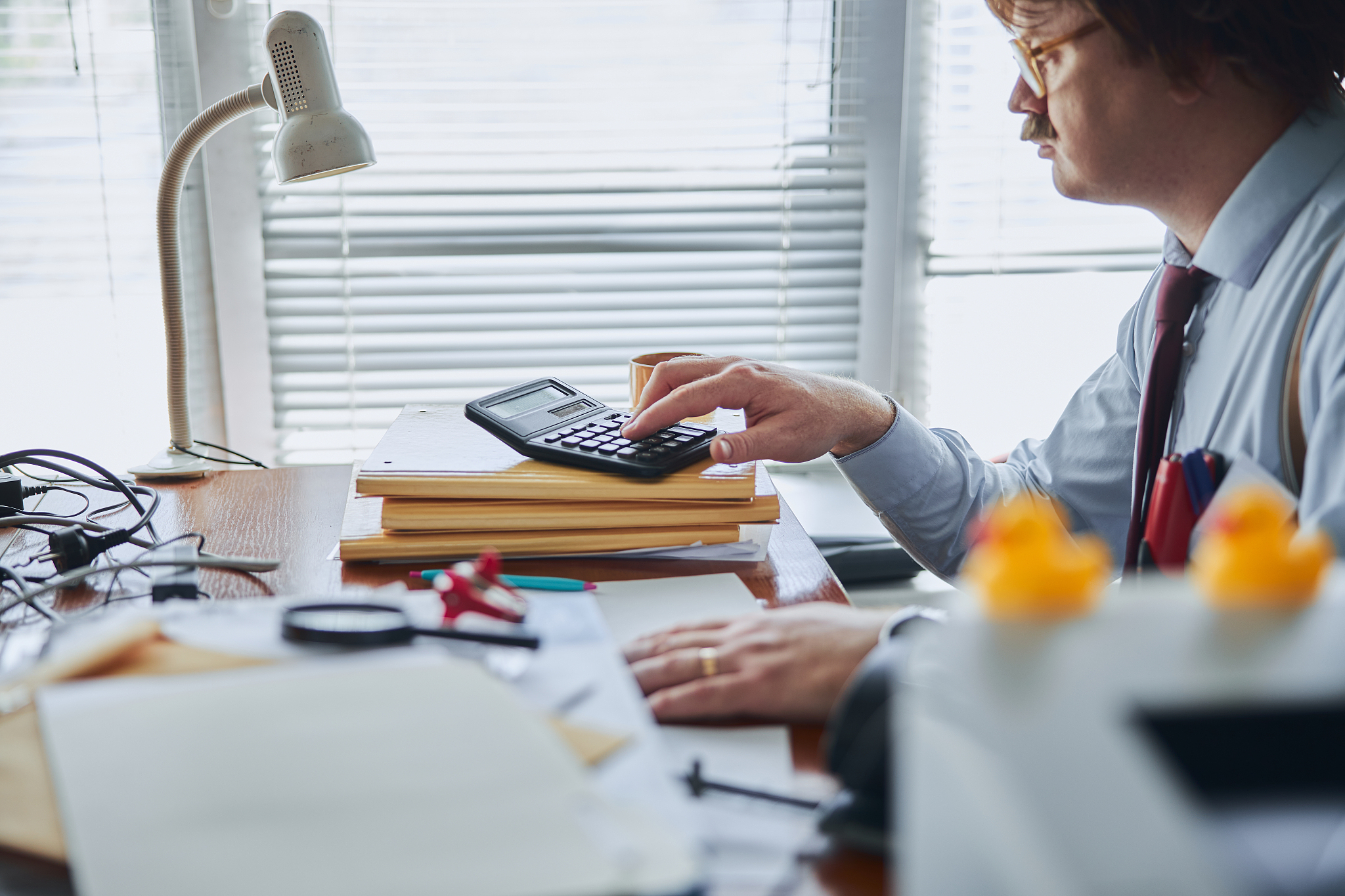 bored man with calculator and pile of documents in the office