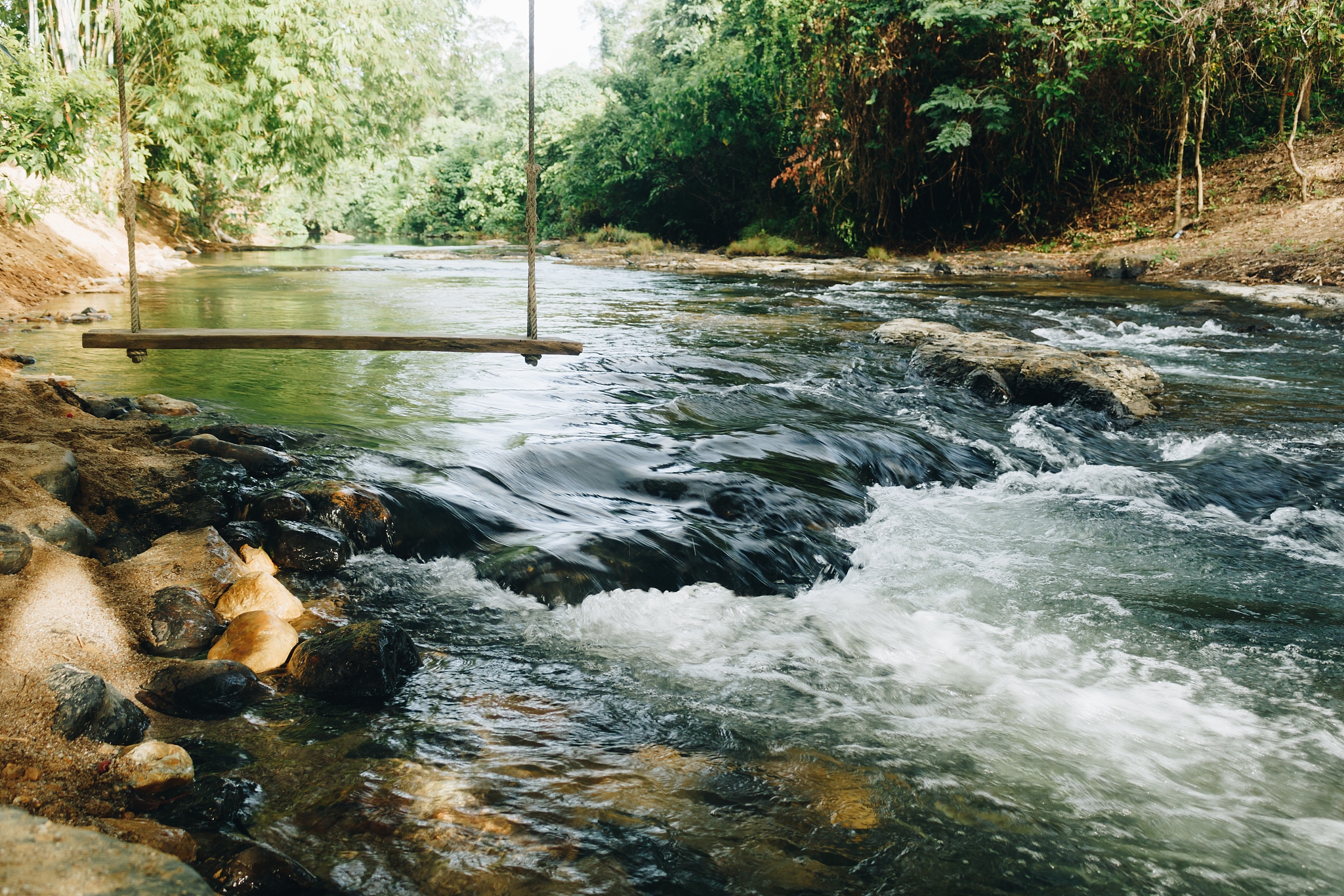 small waterfall in watercourse with wooden swing