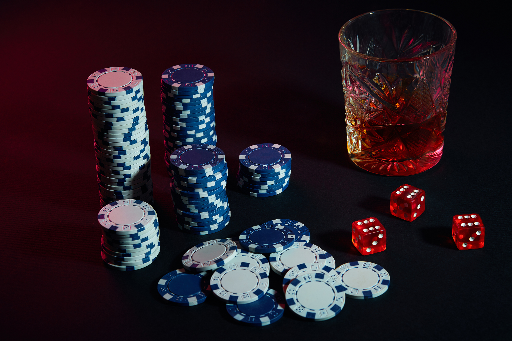 poker chips and wine glass of cognac on dark table. gambling