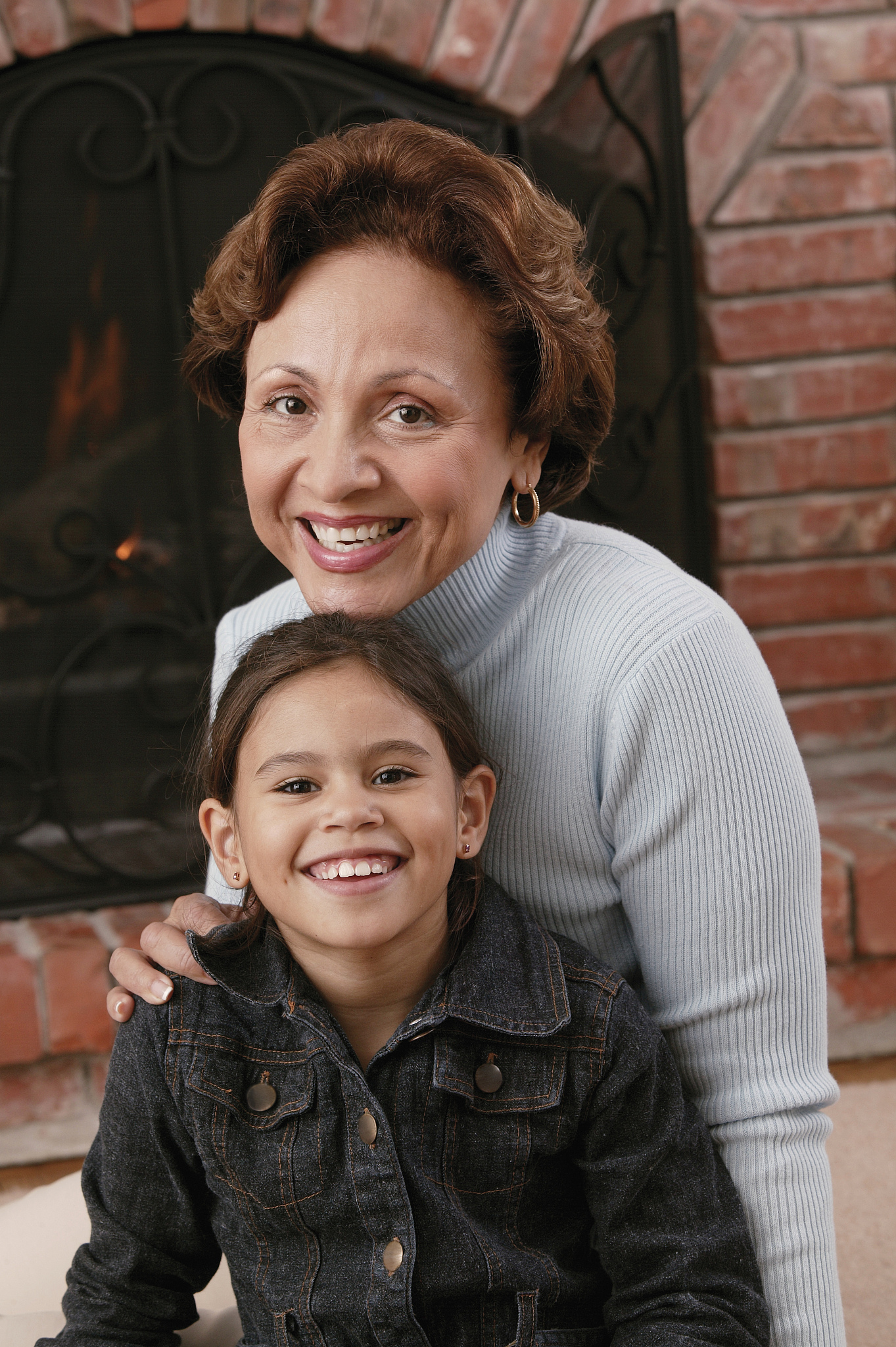 grandmother and granddaughter posing by fireplace