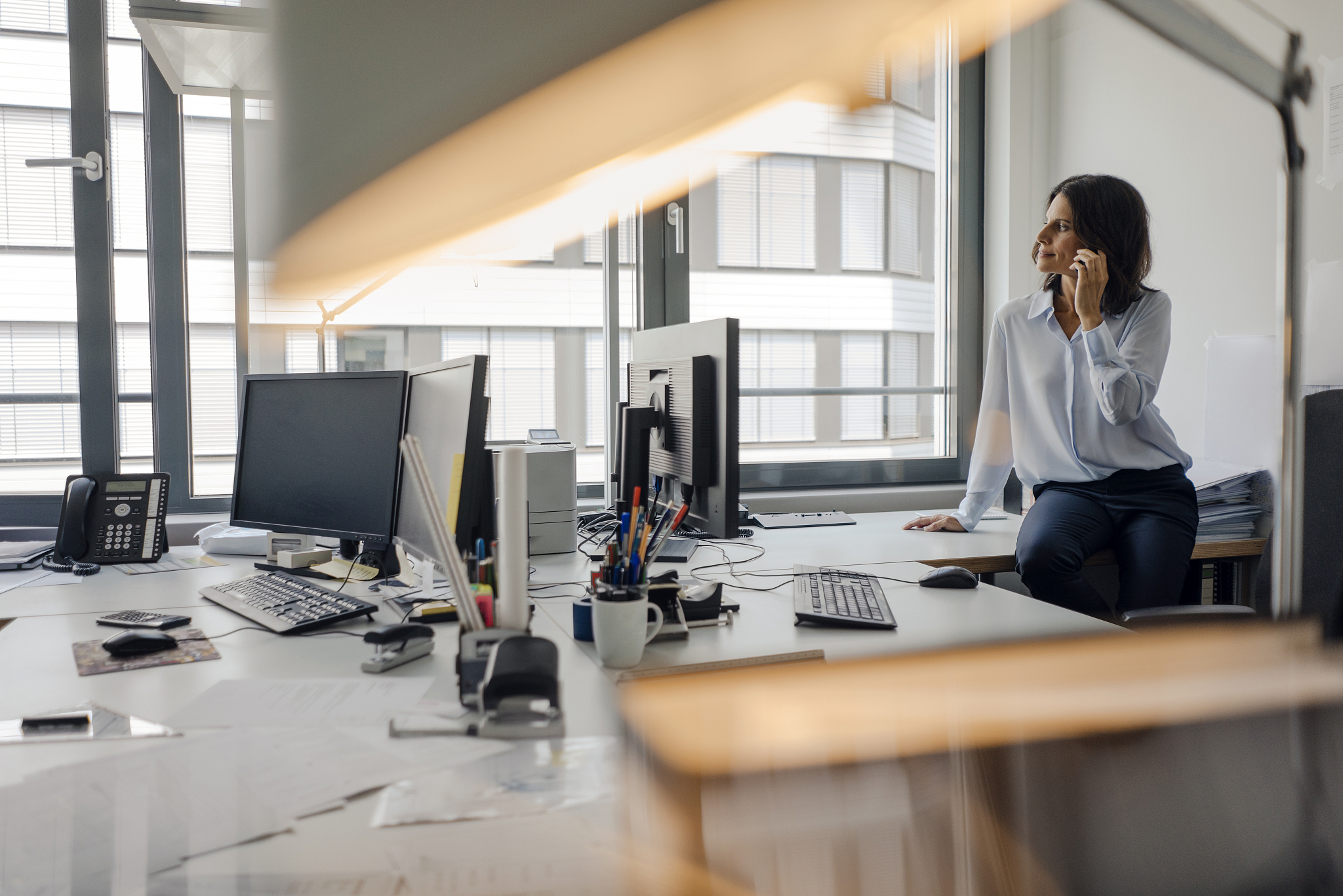 mature businesswoman sitting o desk in office, talking on the ph