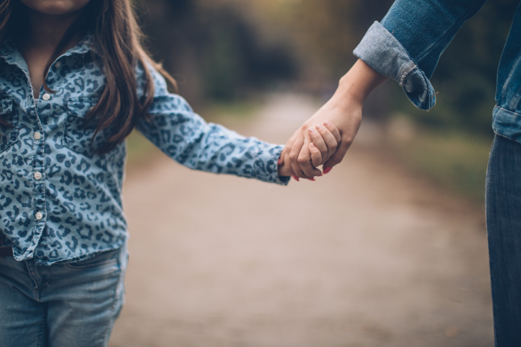 mother and daughter holding hands in park