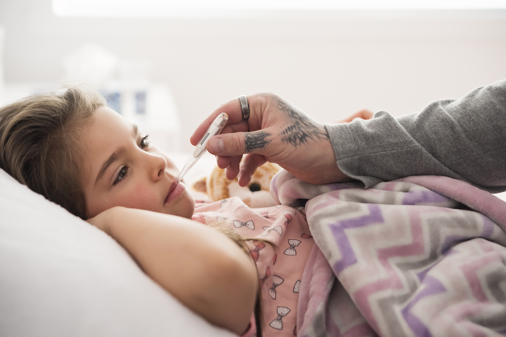 sick little girl lying in bed with thermometer.
